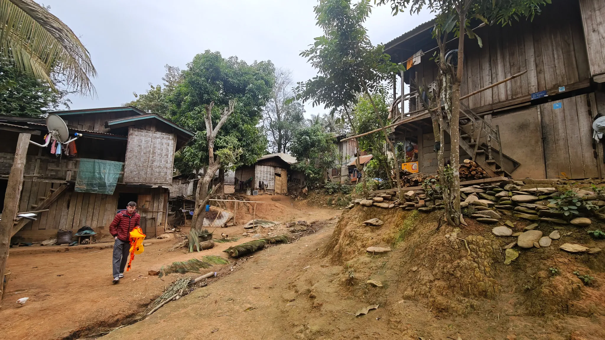 Dirt road through Ban Haddean village with traditional wooden stilt houses and forested hills in Phongsaly Province, Laos