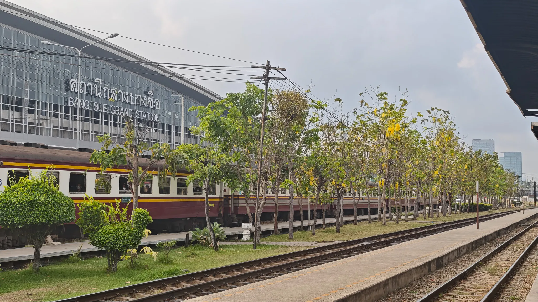 Bang Sue Grand Station in Bangkok with a classic Thai railway carriage parked alongside the modern terminal building