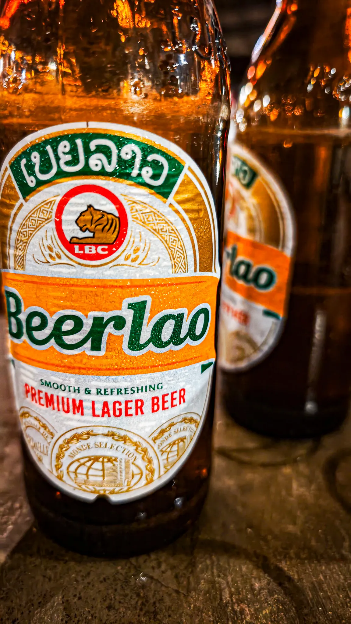 Close-up of a Beerlao premium lager bottle on a wooden table in Muang Ngoi
