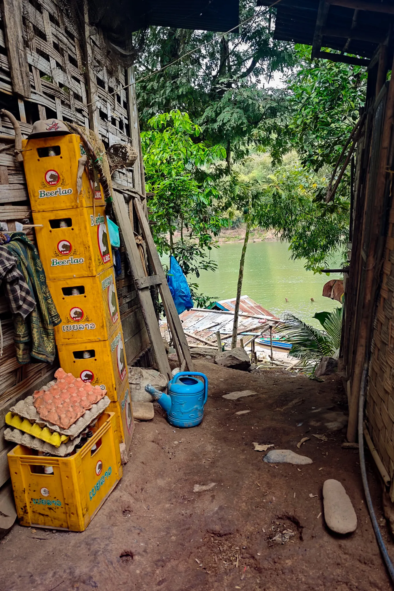 Stacked yellow Beerlao crates and egg trays inside a village store overlooking the Nam Ou river in Phongsaly Province