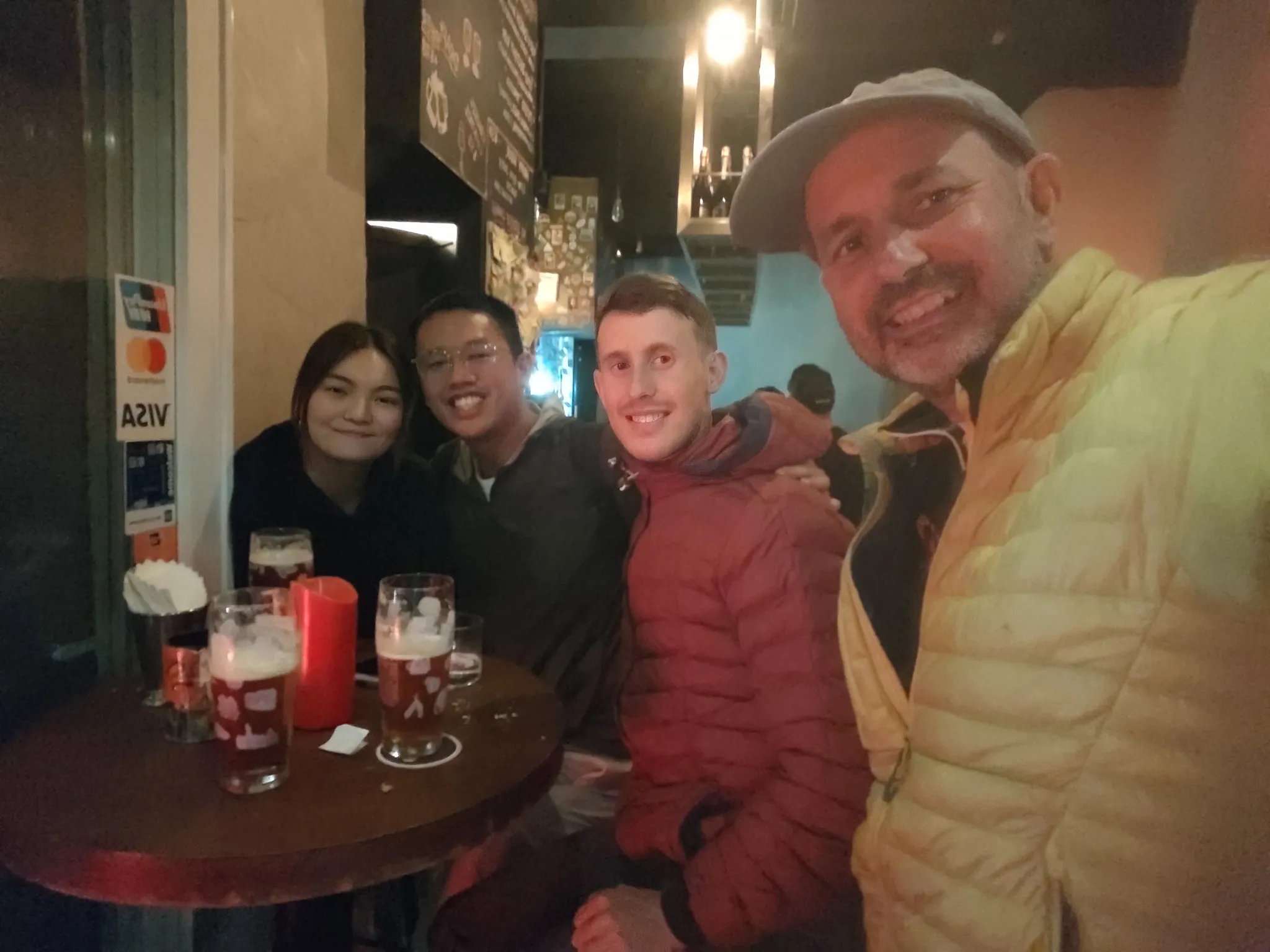 Friends gathered around a small table with beers and a candle at a cosy Belgian bar in Hong Kong