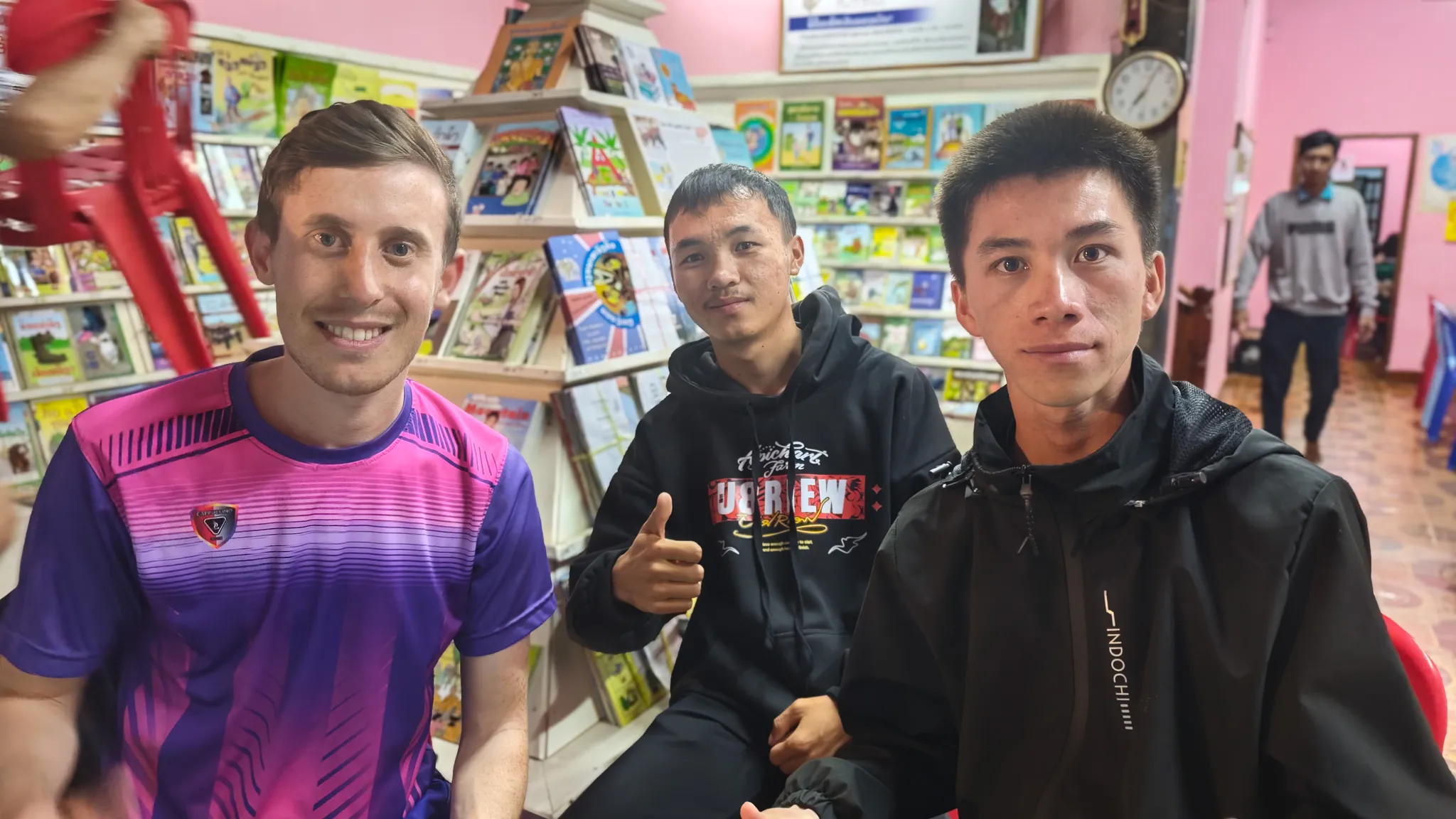 Close-up of a volunteer with Sing and Ying, two 20-year-old Mong students, at Big Brother Mouse in Luang Prabang