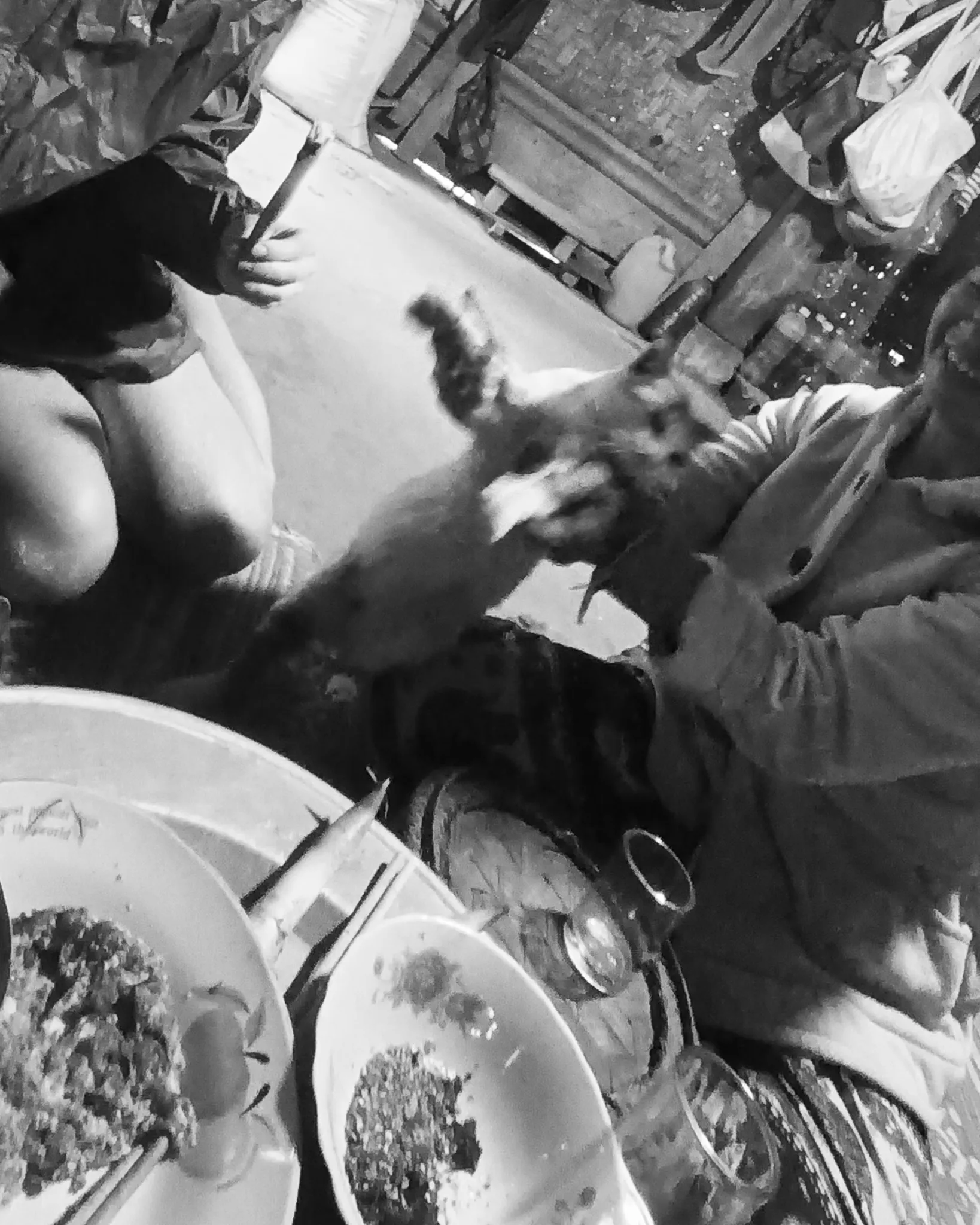 Black and white photo of breakfast being served with plates of food at a villagers home along the Nam Ou river in Laos