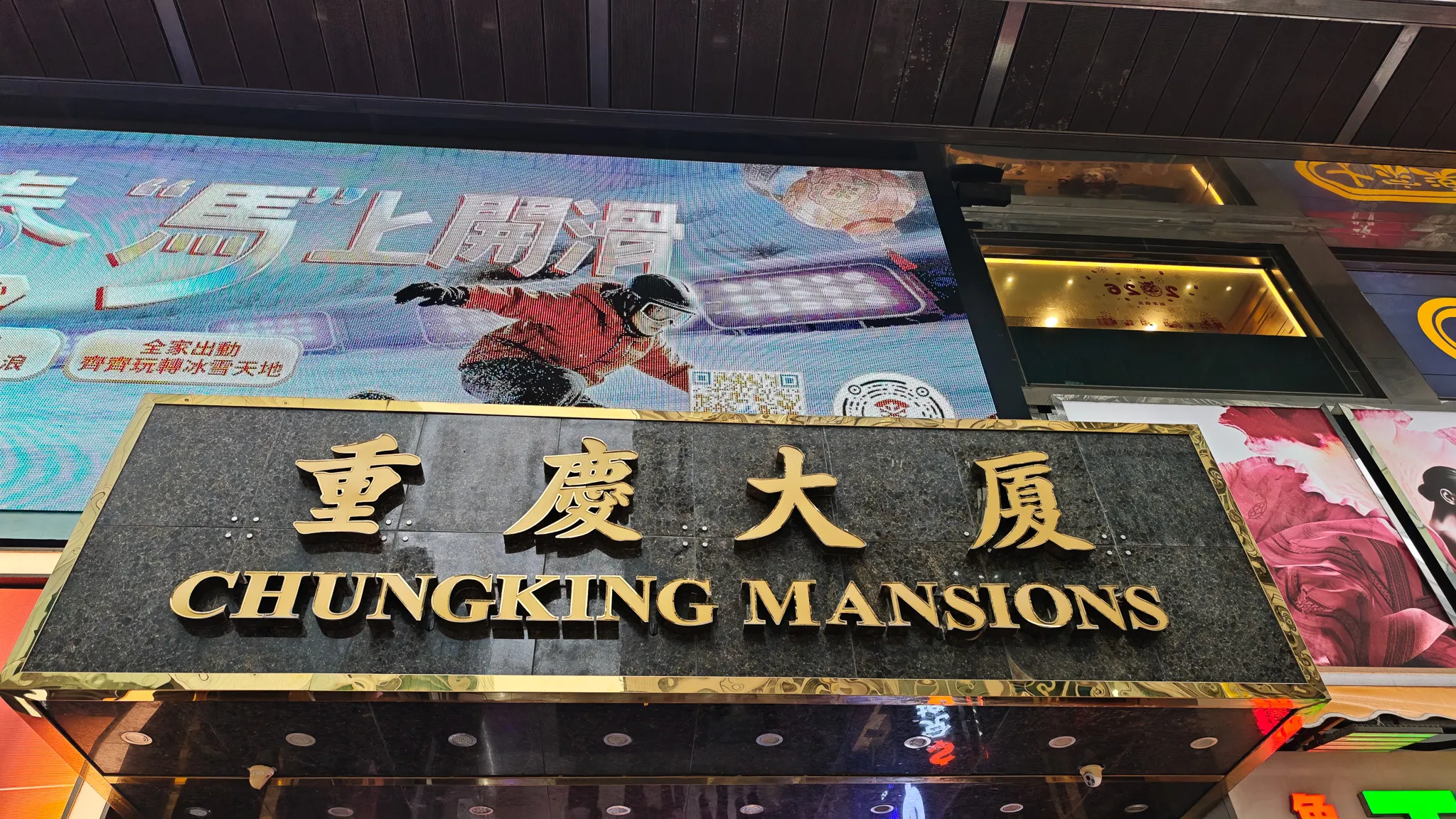 Chungking Mansions entrance sign in gold lettering with Chinese characters above the Kowloon building entrance