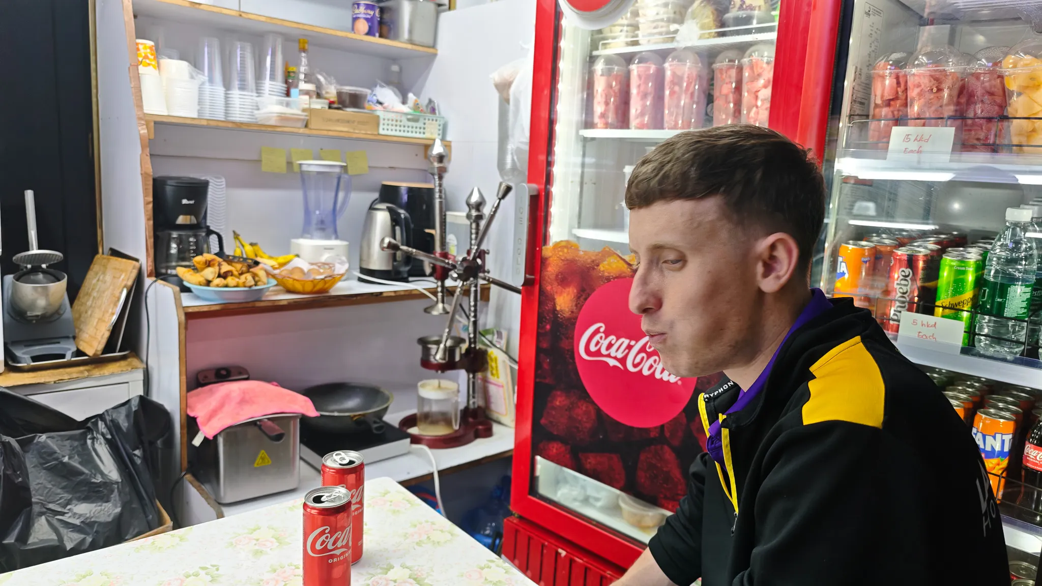Friend sitting at a tiny Chungking Mansions food counter late at night with samosas being prepared behind