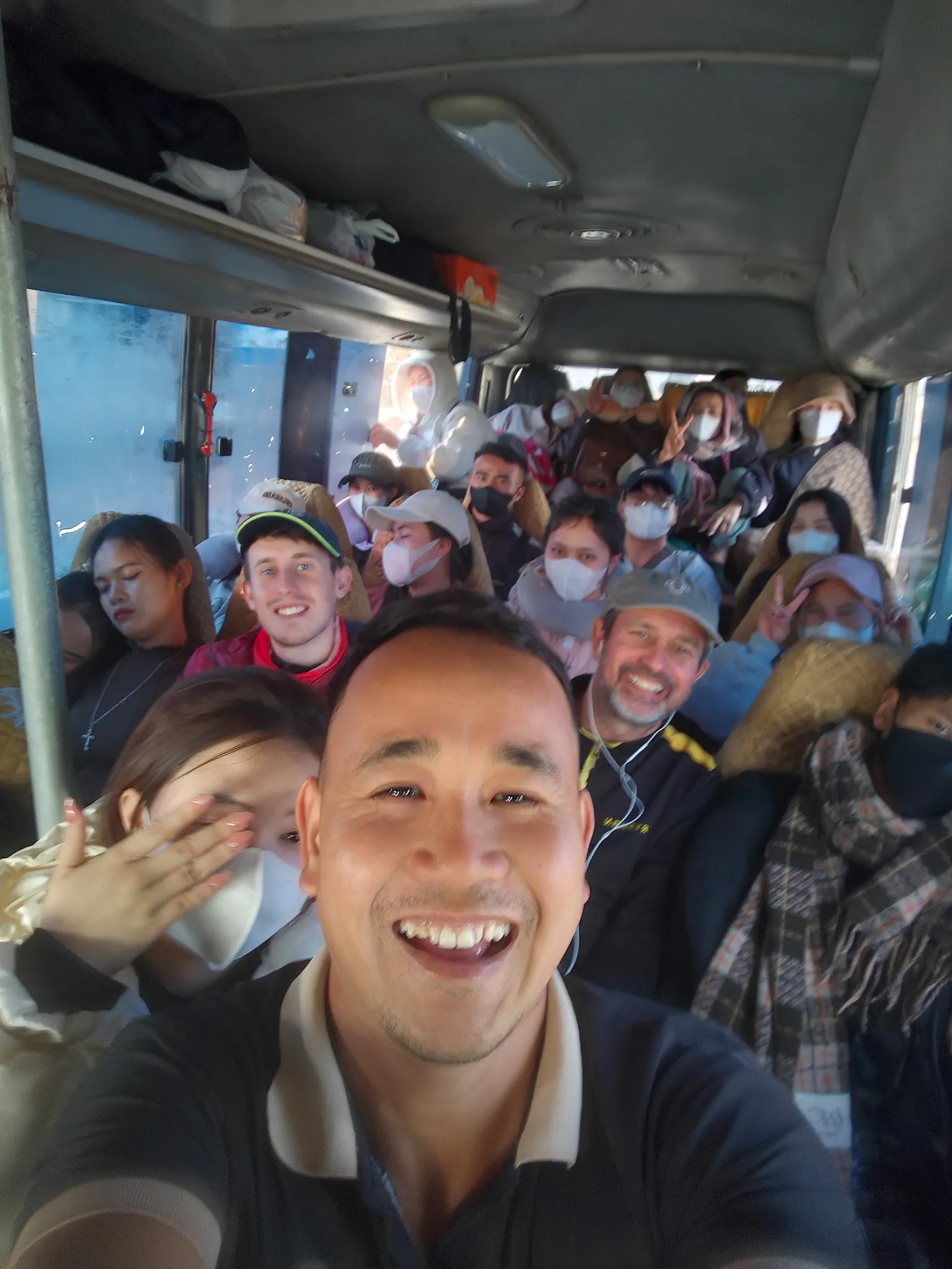 Smiling passengers crammed into the overloaded minibus on the route from Dien Bien Phu to Laos