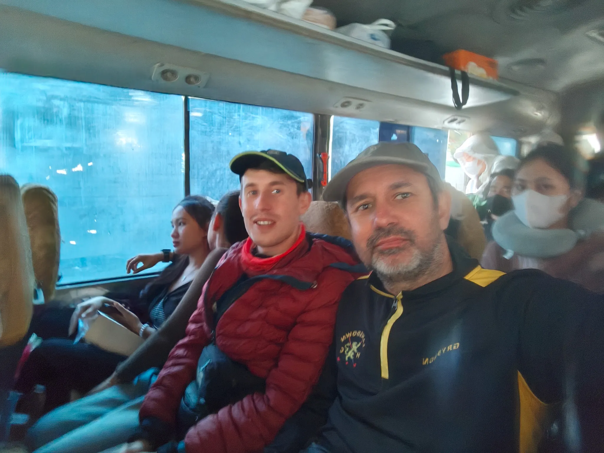 Selfie of two travellers squeezed into the crowded Dien Bien to Muang Khua minibus with Vietnamese passengers