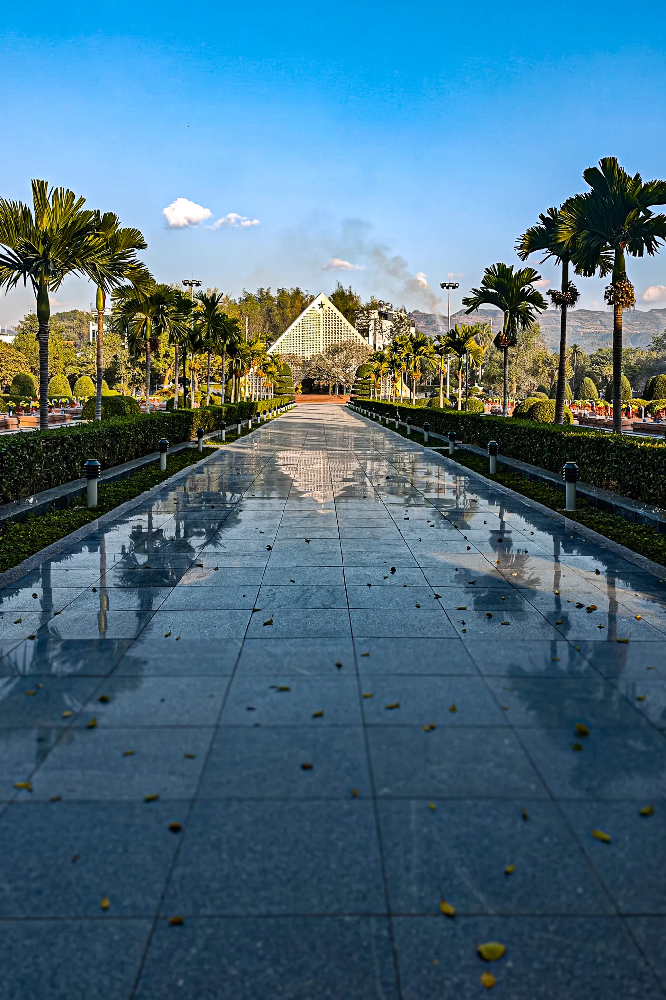 Long reflective pathway lined with palm trees leading to the Dien Bien Phu memorial pyramid with gold star