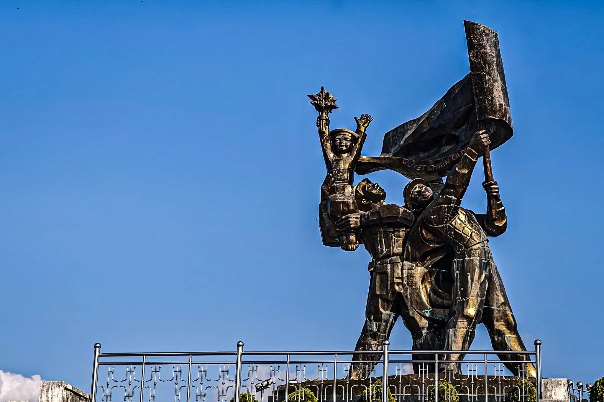 Bronze victory monument at Dien Bien Phu showing Vietnamese soldiers raising a flag and star — commemorating the 1954 defeat of French colonial forces