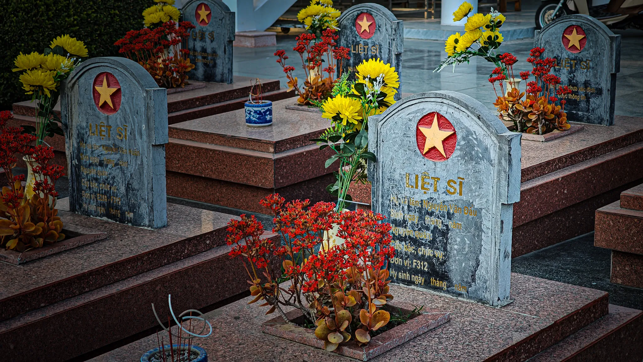 Vietnamese war graves at Dien Bien Phu marked with red and gold stars, decorated with yellow chrysanthemums and red flowers