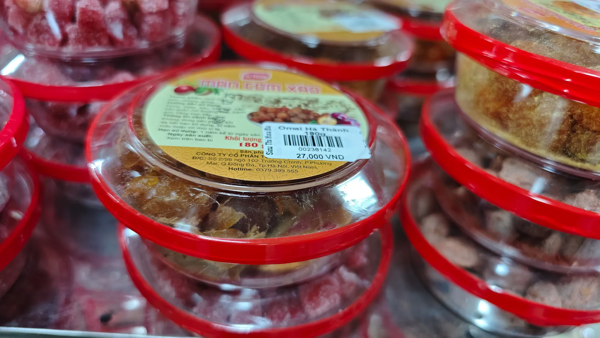 Stacked containers of traditional Vietnamese sweets and preserved fruits at a Dien Bien Phu supermarket priced in VND