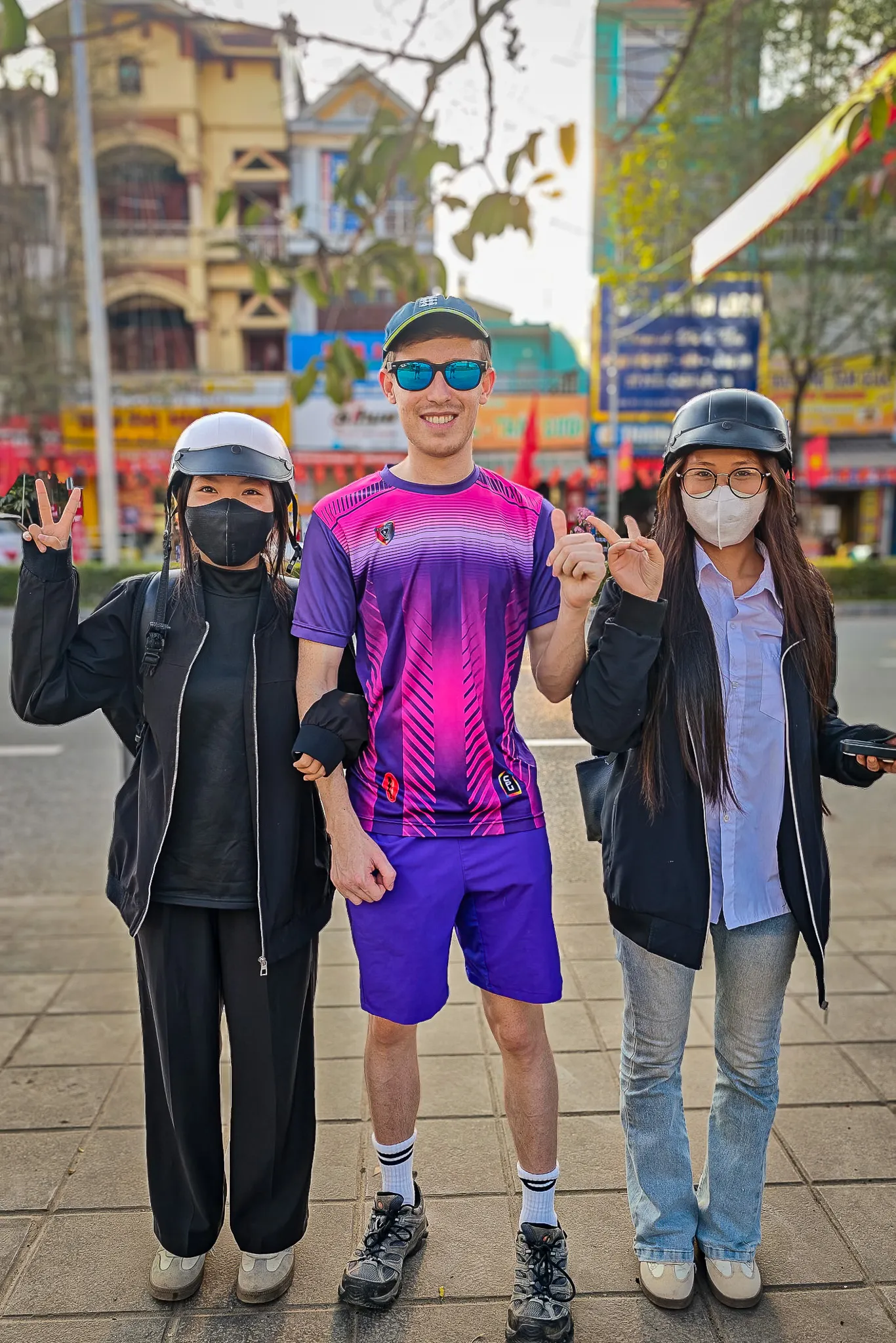 Posing with two local friends wearing motorbike helmets on a Dien Bien Phu street with Vietnamese signage