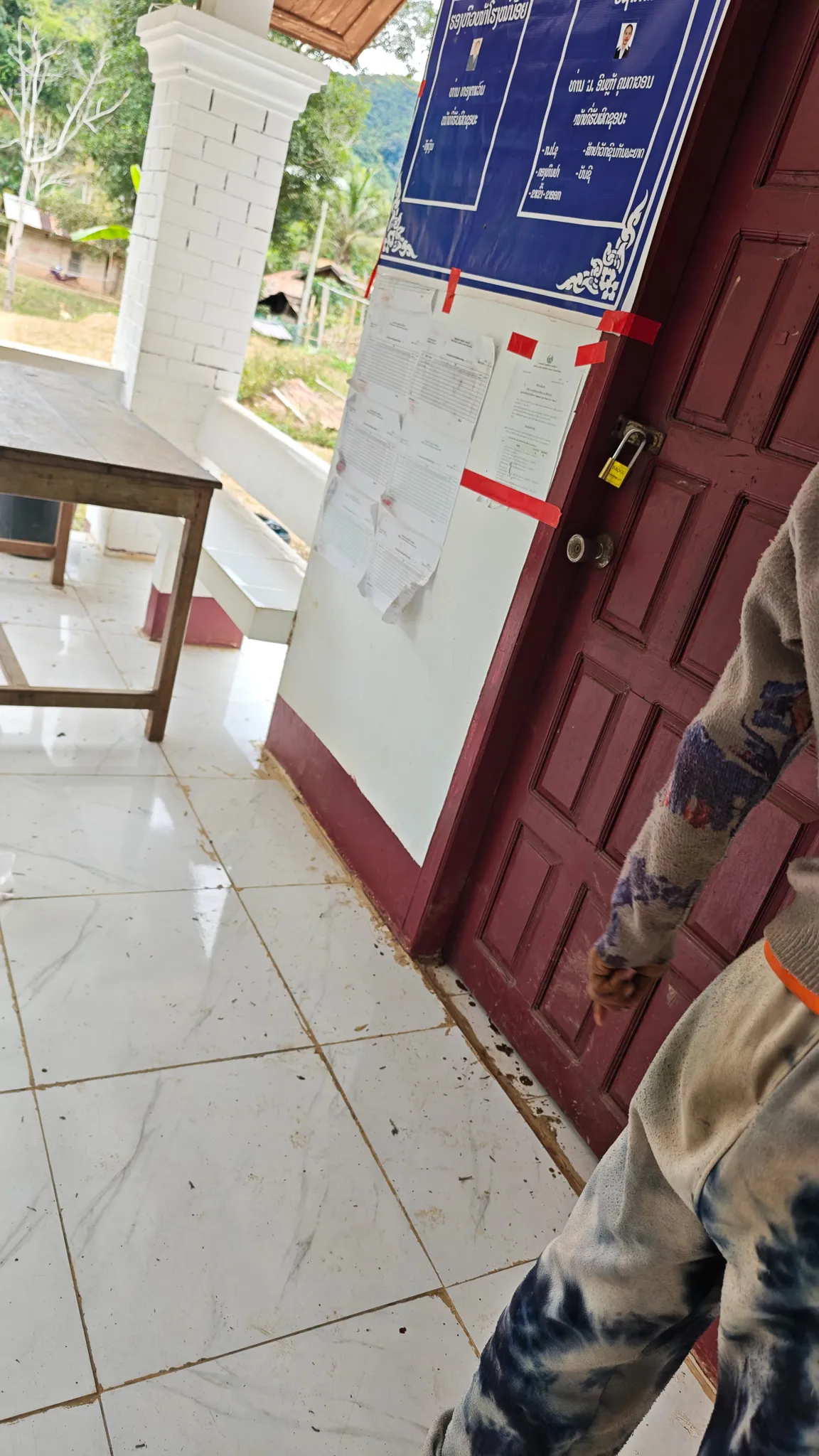 Entrance to the Ban Haddean health centre with official Lao government notices taped to a red door, Phongsaly Province