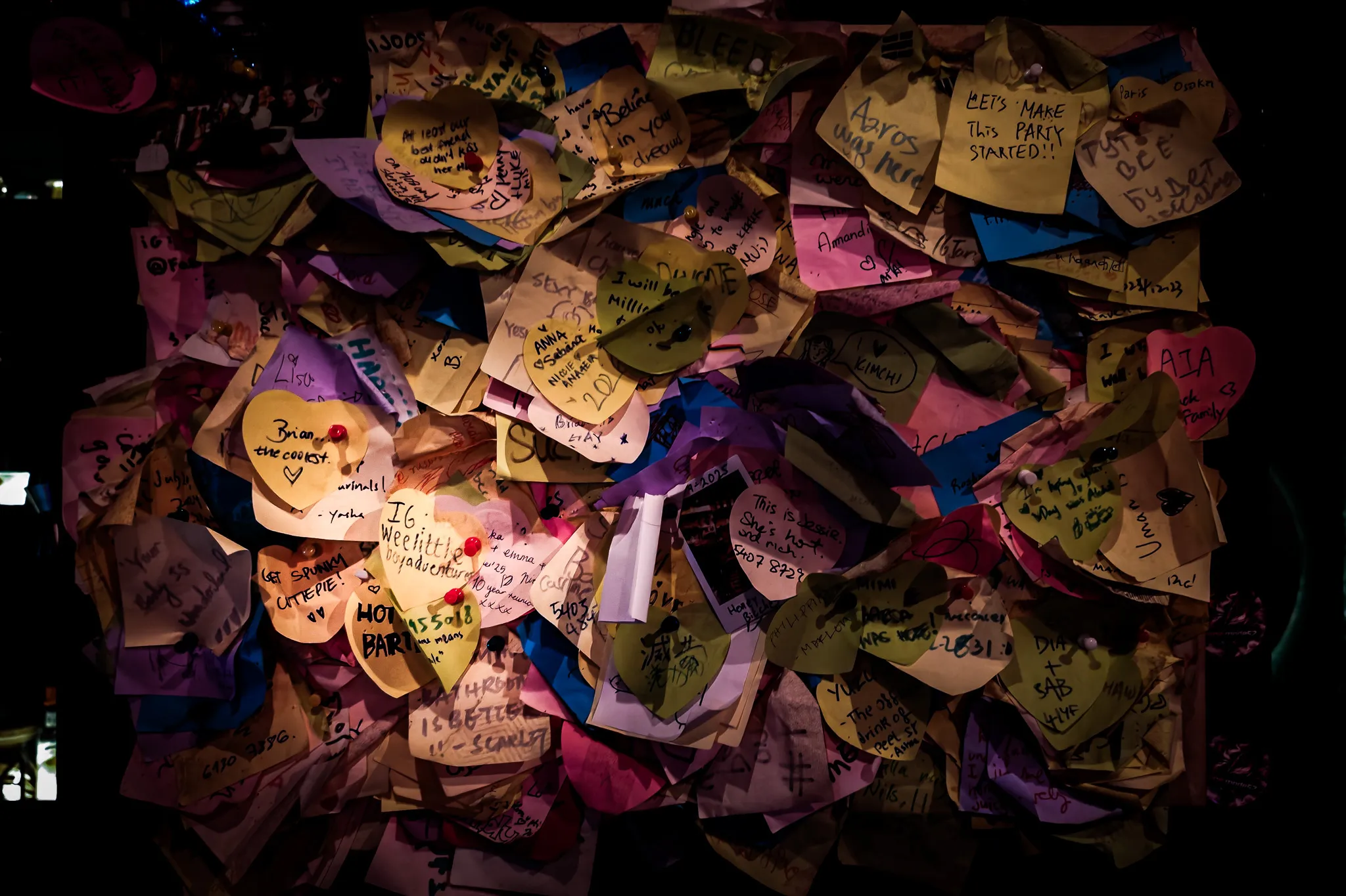 Close-up of colourful heart-shaped sticky notes with messages left by visitors on a Hong Kong bar wall