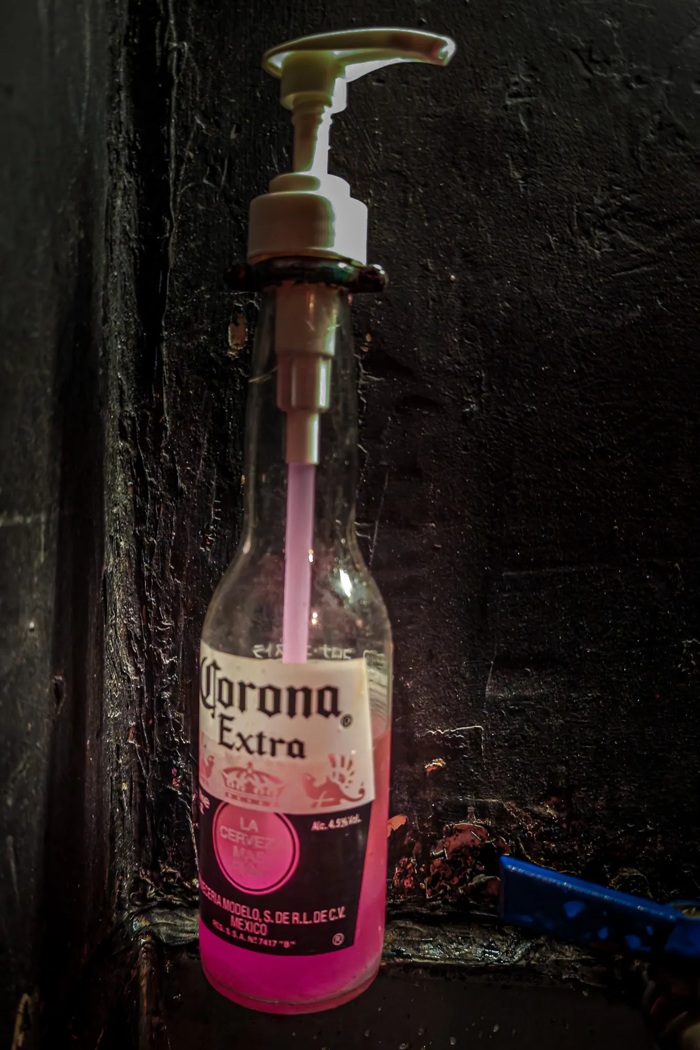 Corona Extra beer bottle repurposed as a pink soap dispenser in a Hong Kong bar bathroom