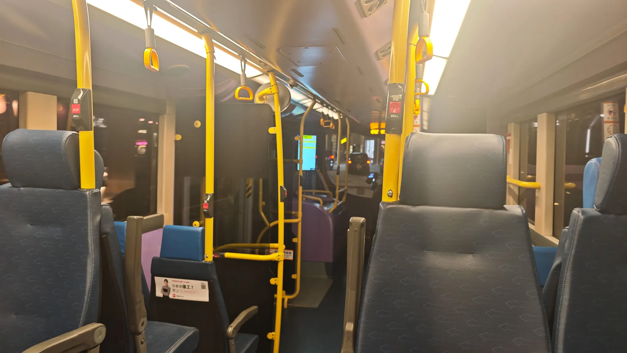 Empty interior of a Hong Kong night bus with yellow handrails heading back through Wan Chai