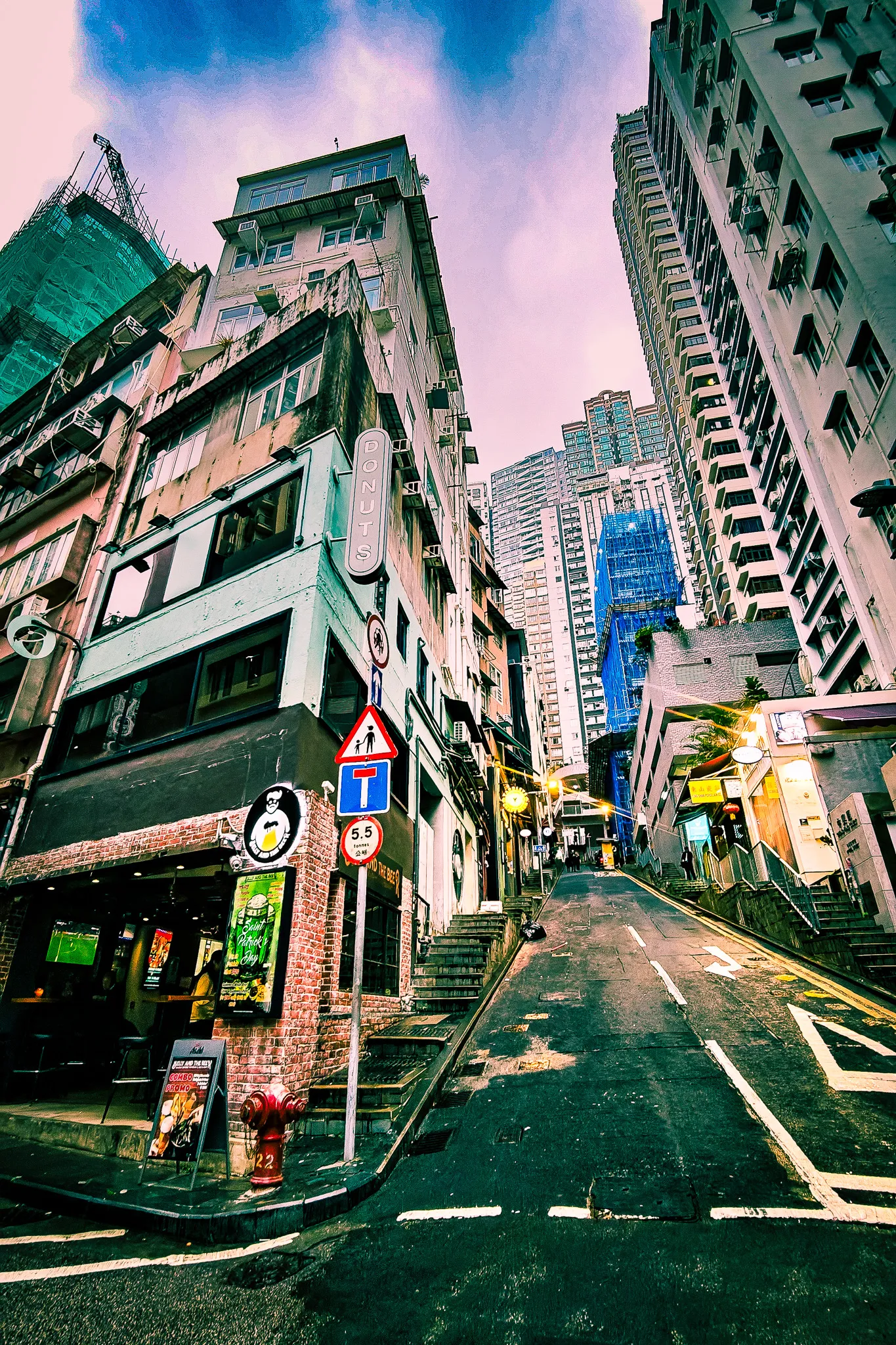 Steep Hong Kong street with stone steps alongside a road, surrounded by tall buildings in the Central district