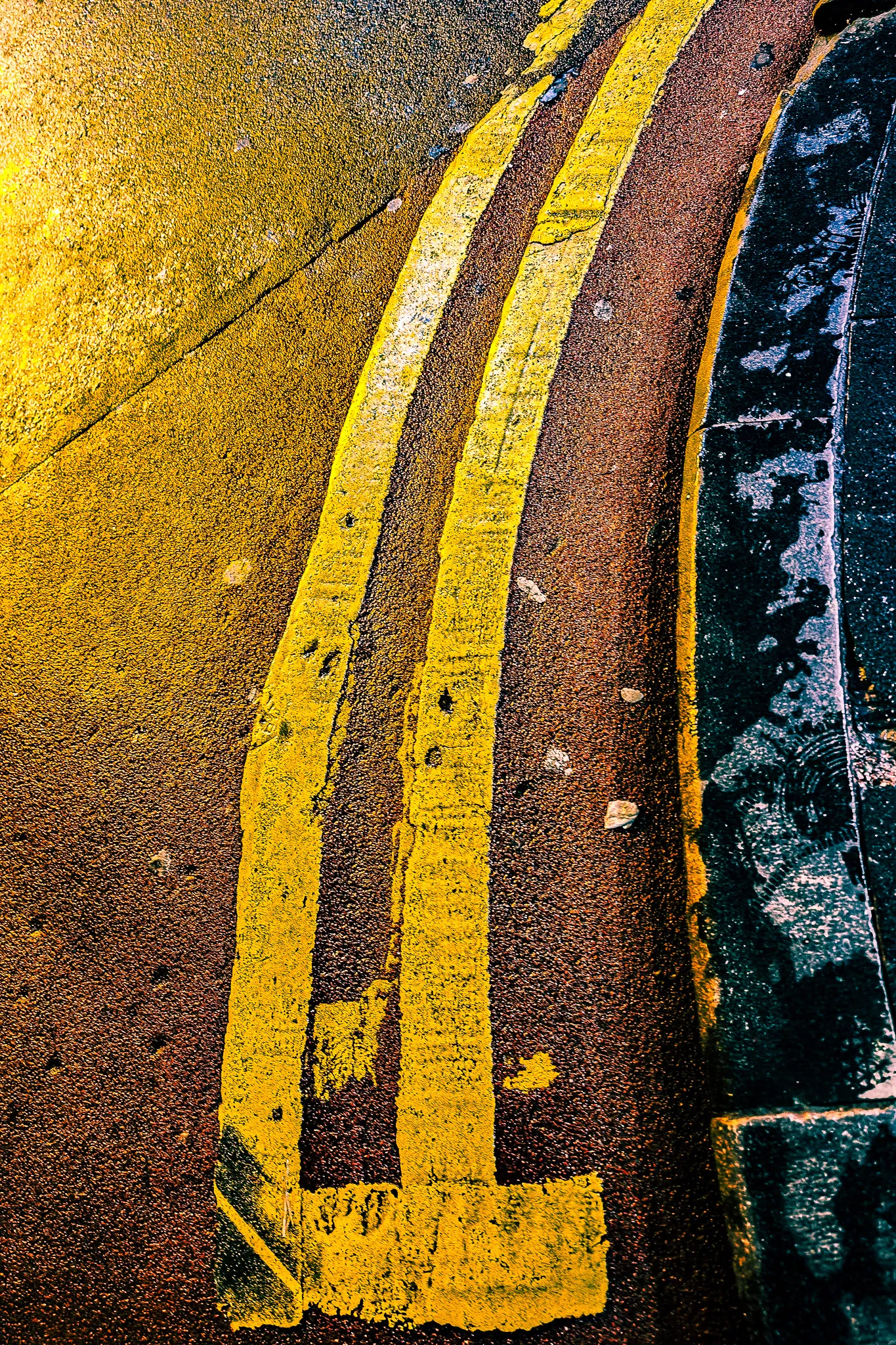 Close-up of yellow double road markings curving around a kerb on a wet Hong Kong street at night