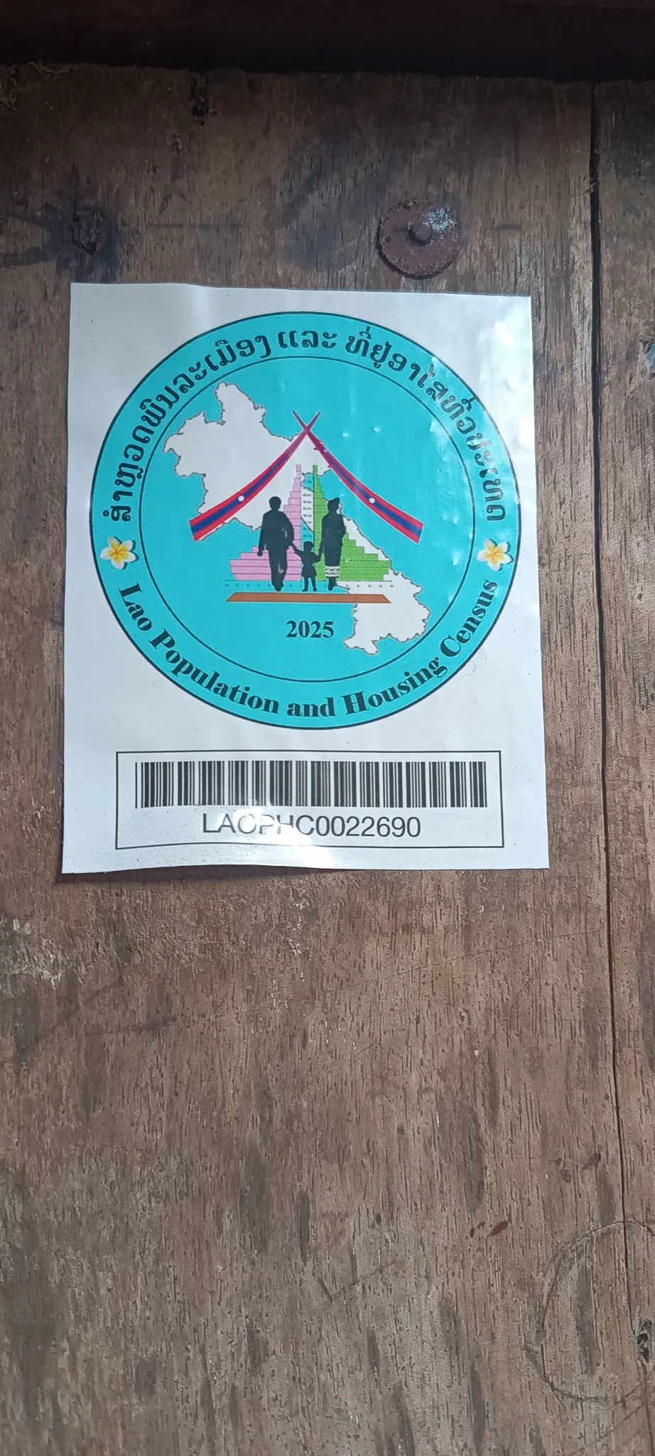 Lao Population and Housing Census 2025 sticker with barcode on a wooden door in Ban Haddean village, Phongsaly Province