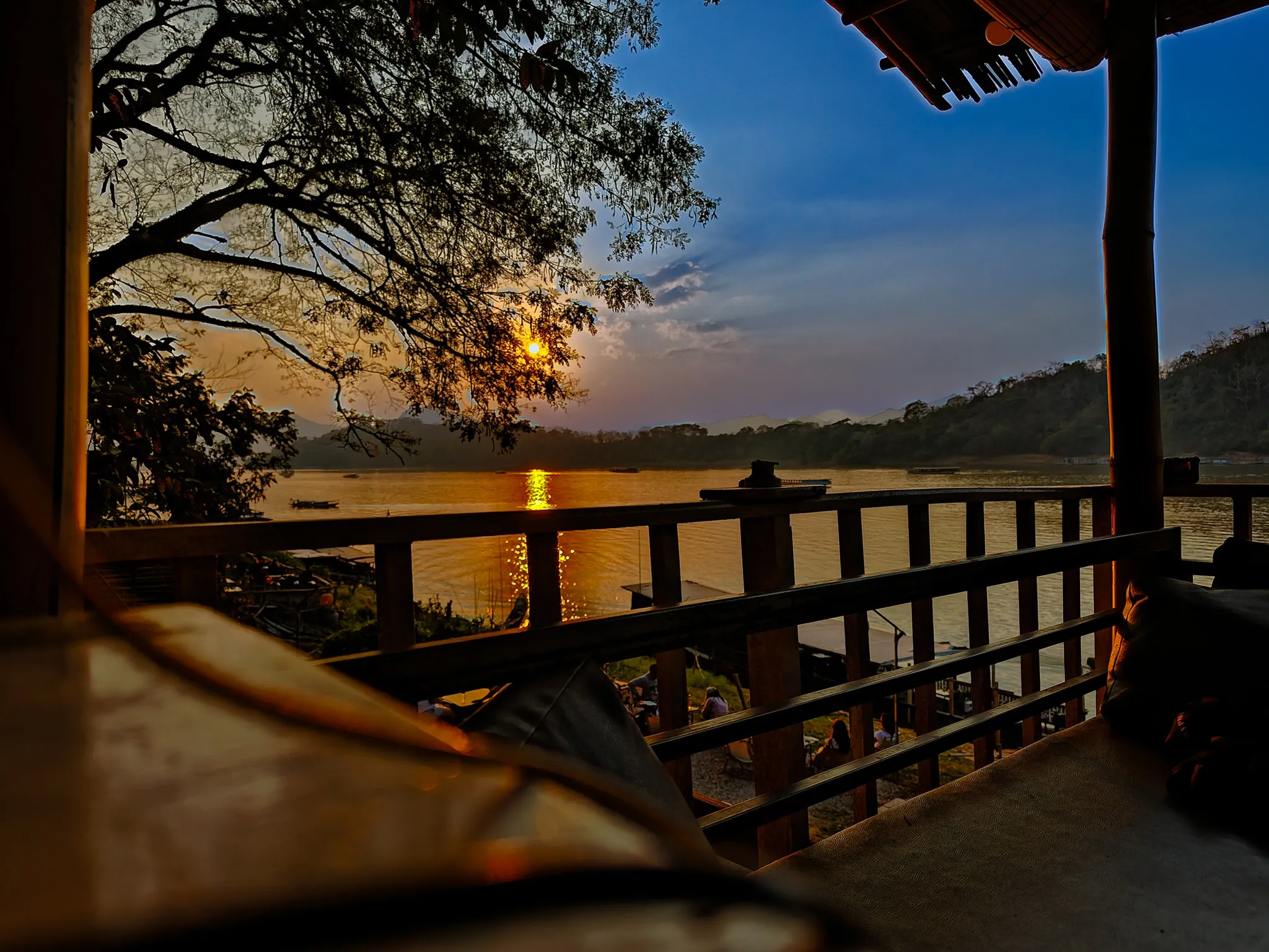 Golden sunset over the Mekong River seen from a wooden terrace in Luang Prabang
