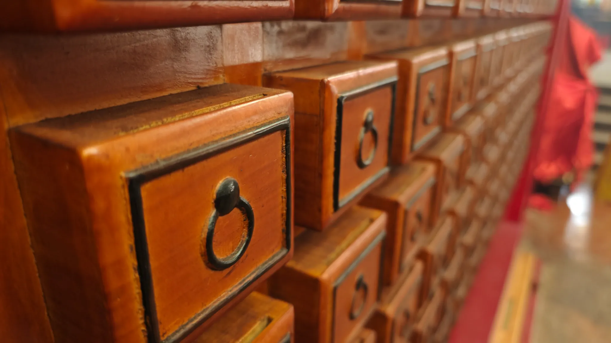 Rows of traditional wooden fortune-telling drawers with iron ring handles inside a Hong Kong temple
