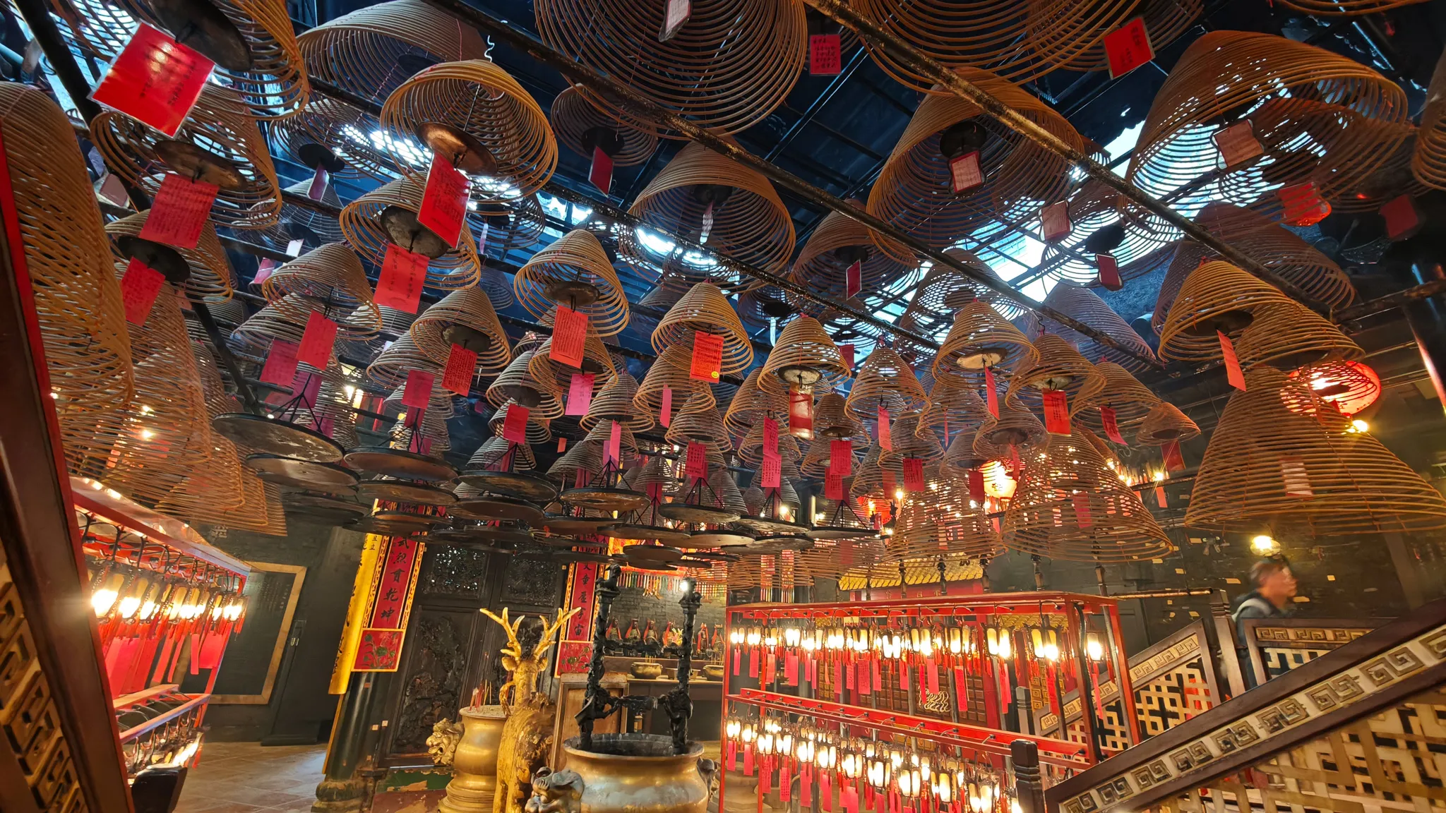 Dozens of hanging incense coils with red prayer tags filling the ceiling of Man Mo Temple