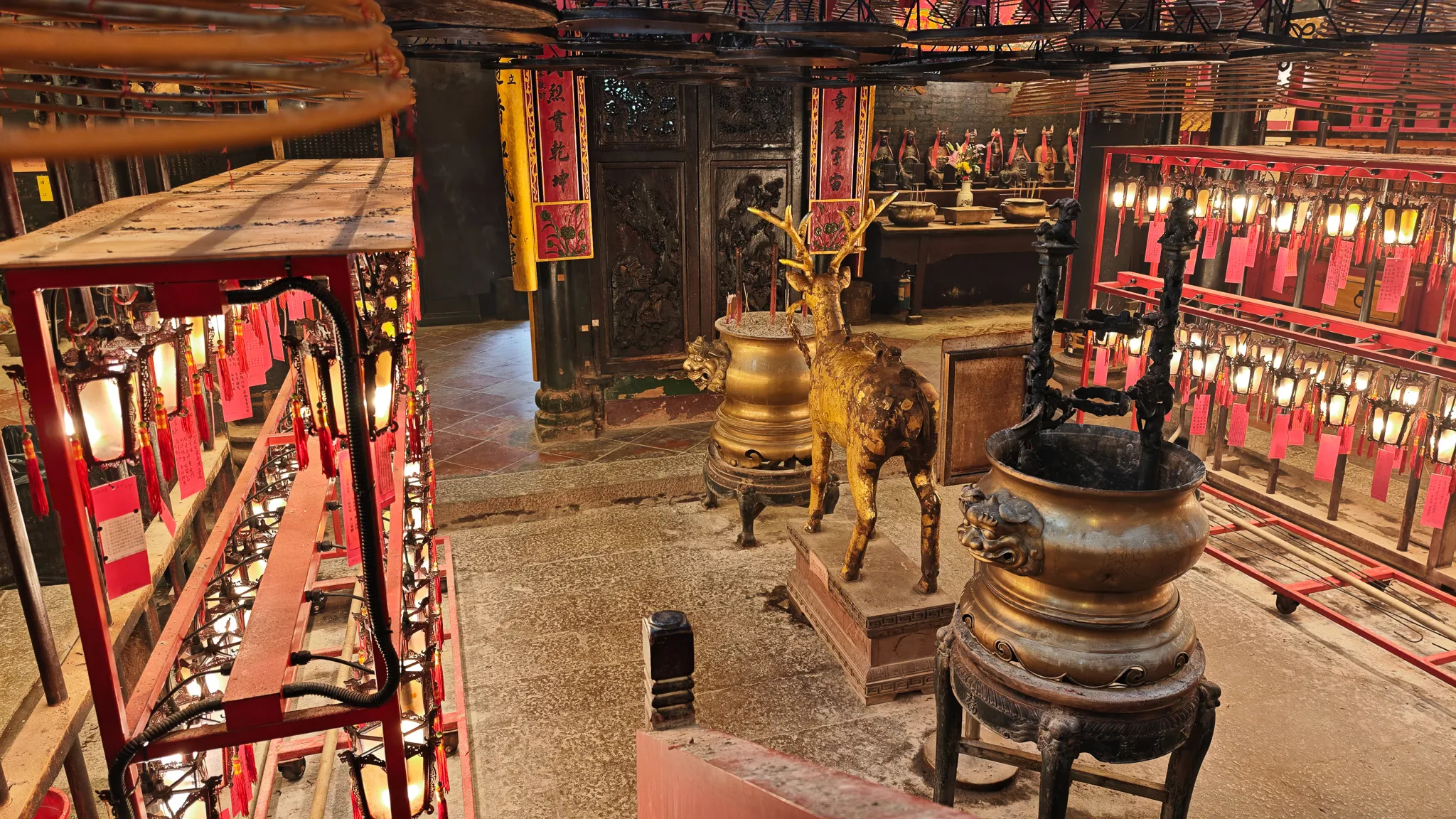 Interior of Man Mo Temple with bronze deer statue, incense burners and red prayer tablets