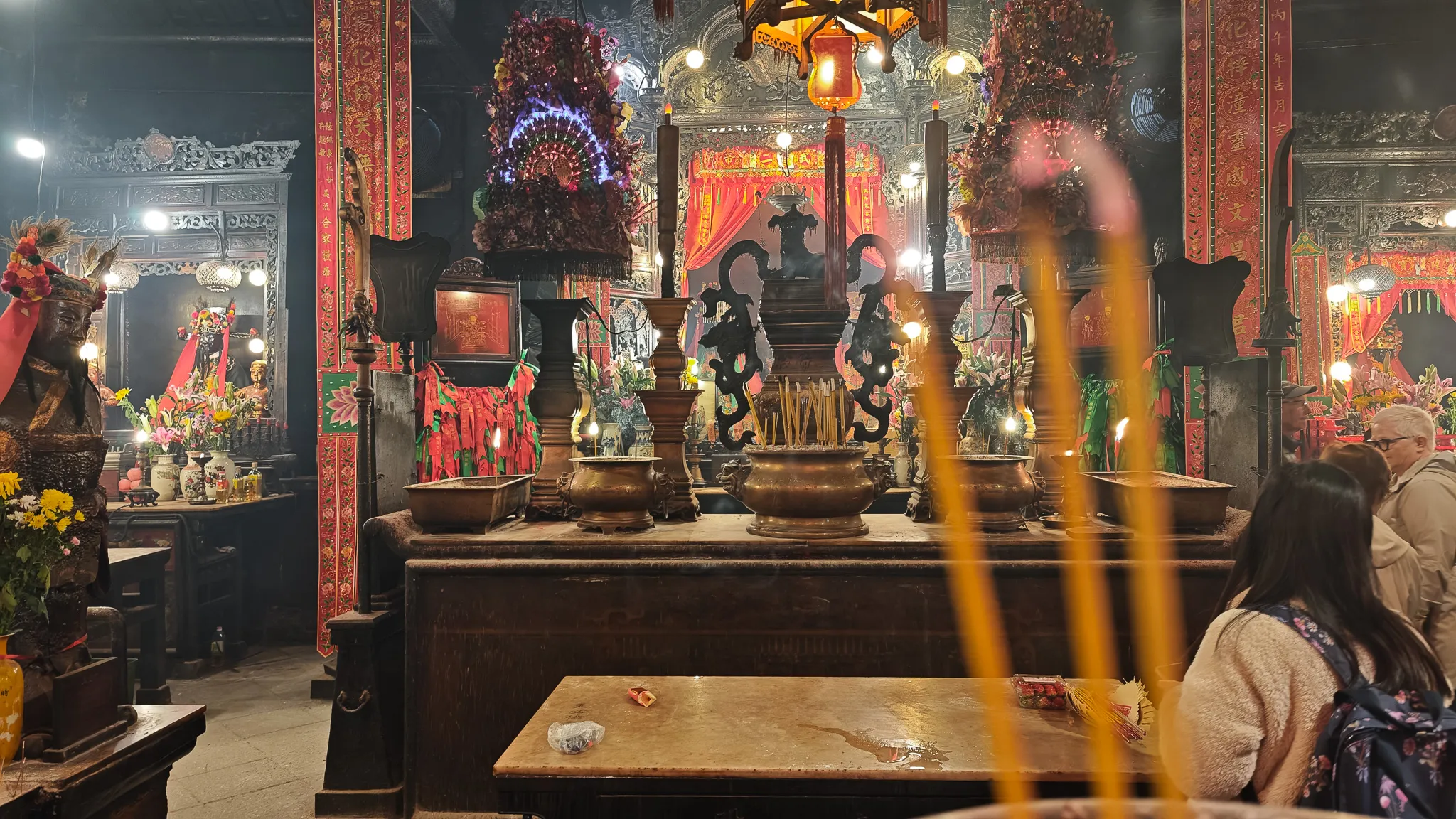 Main altar inside Man Mo Temple with brass urns, incense sticks and ornate carved decorations