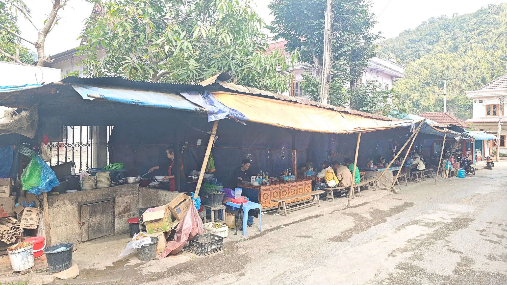 Wide view of the market stalls lining the main street in Muang Khua, Laos, with vendors and makeshift canopy roofs