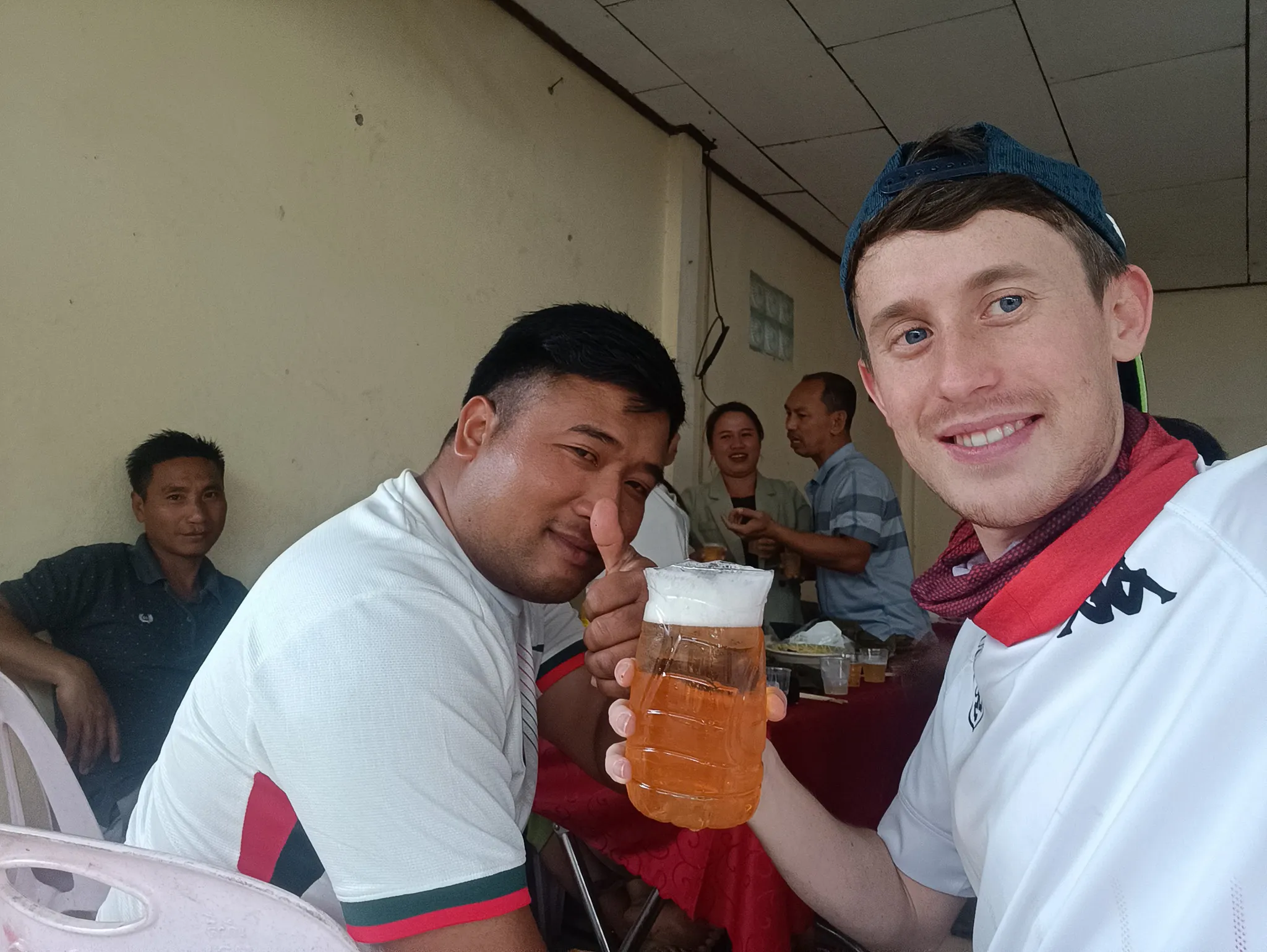 Selfie of traveller sharing a large Beer Lao with a local friend at the community party in Muang Khua