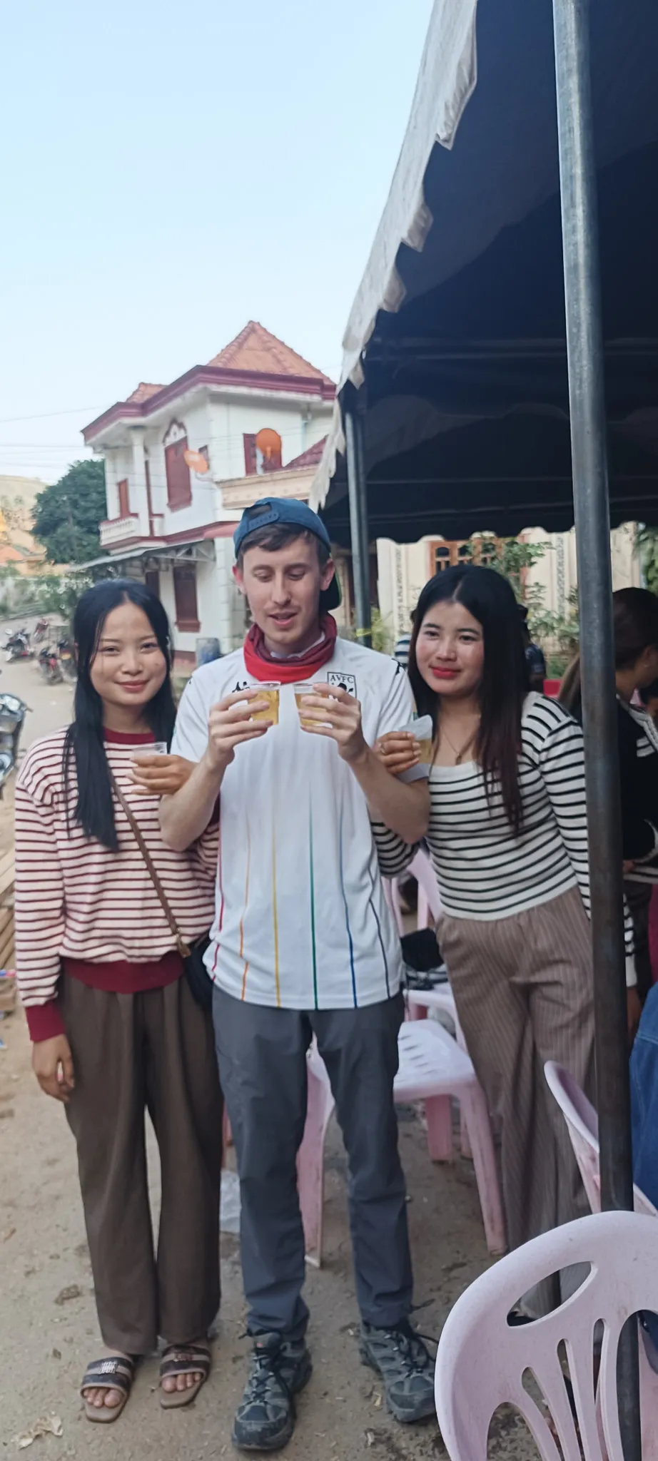 Traveller and two Lao women raising their glasses for a toast at the community celebration in Muang Khua