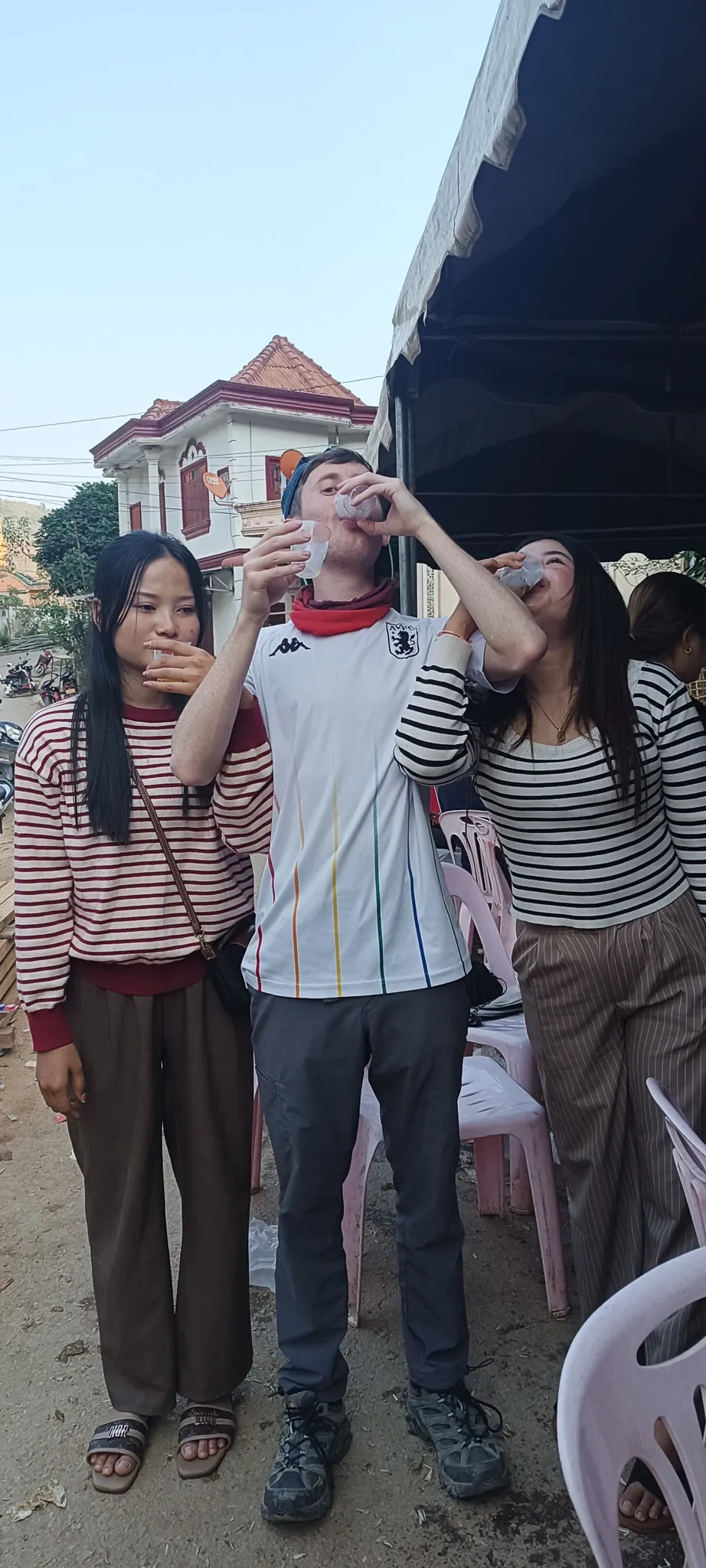 Traveller and local women finishing their drinks at the community celebration in Muang Khua, Laos