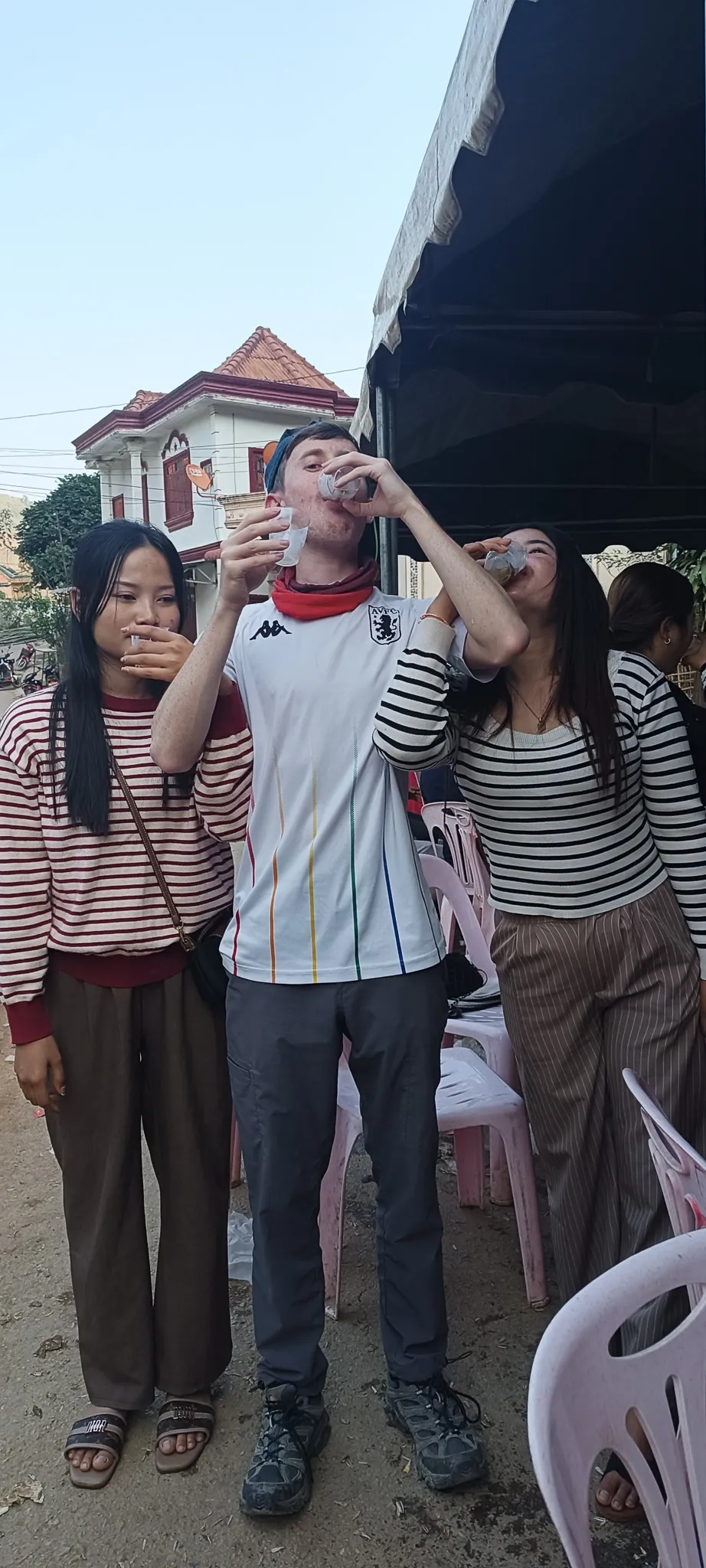 Traveller and two local women drinking shots of Lao whisky together at the Muang Khua party