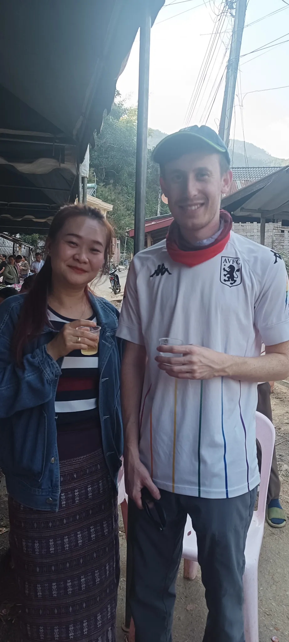 Traveller and local woman holding drinks together at a community gathering in Muang Khua, Laos
