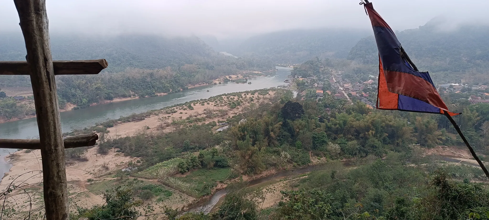 Panoramic view from Muang Ngoi viewpoint over the Nam Ou river and village with a Lao flag
