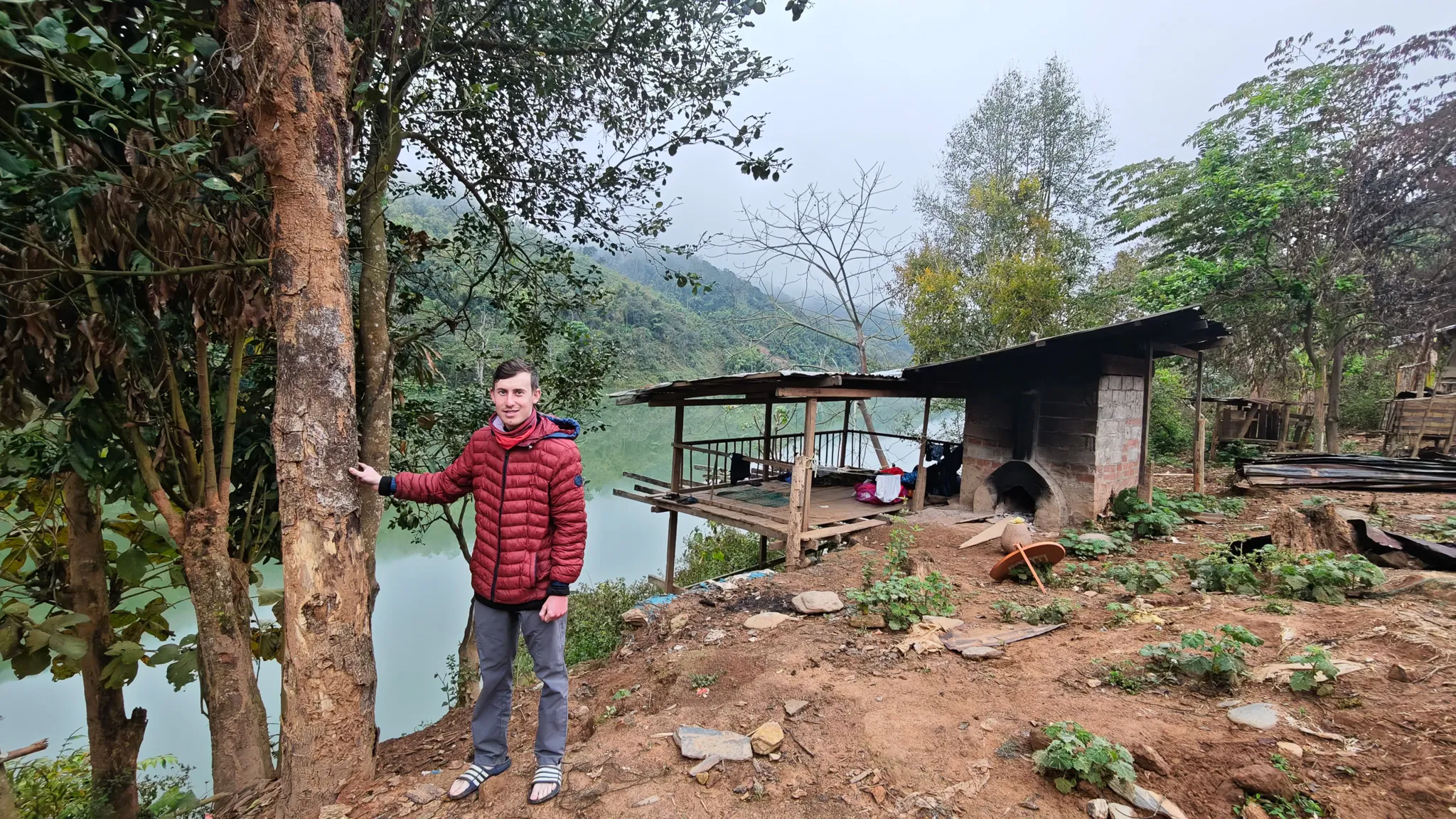 Paddler posing by a tree near a riverside shelter on the banks of the Nam Ou river in Laos