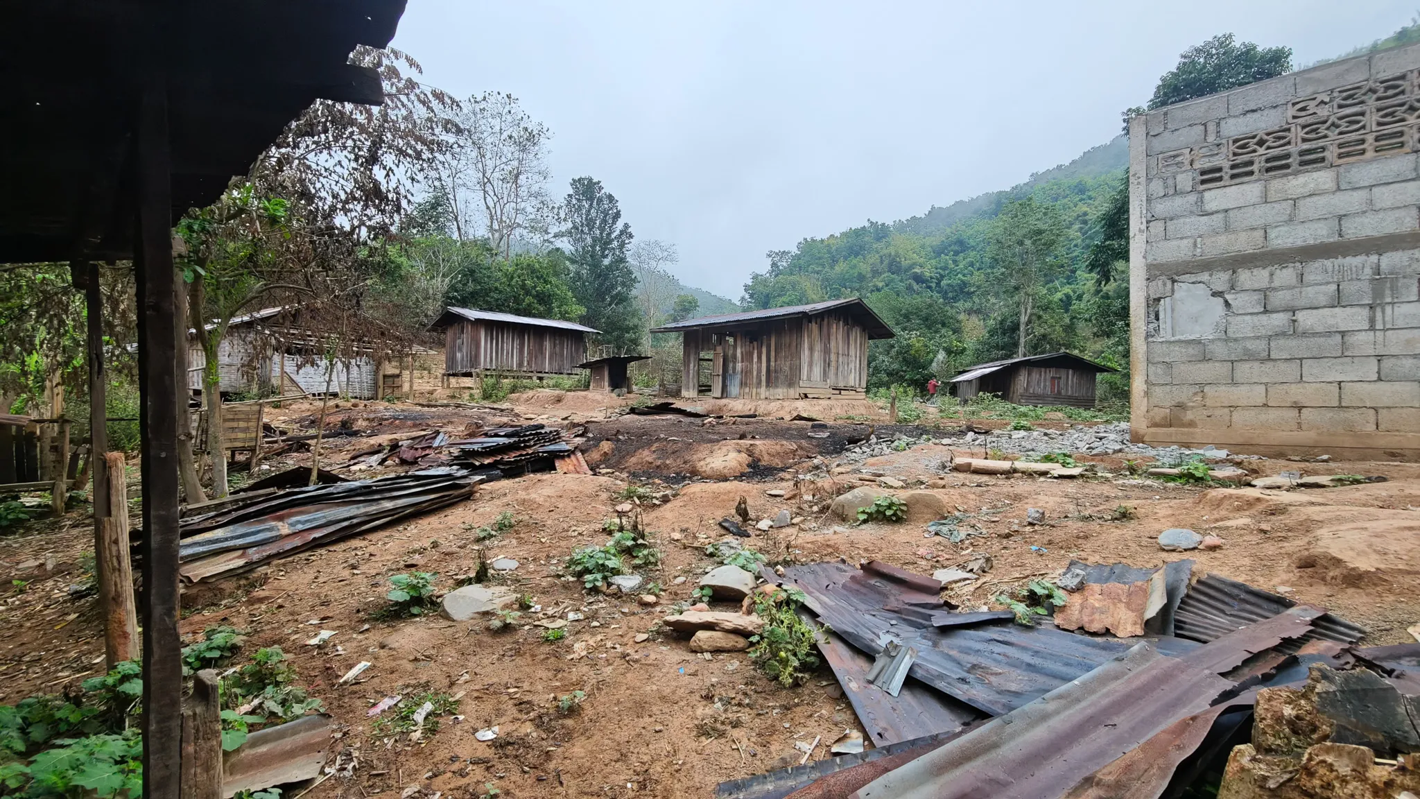 Wooden houses and corrugated iron roofing in a hillside village along the Nam Ou river on an overcast morning