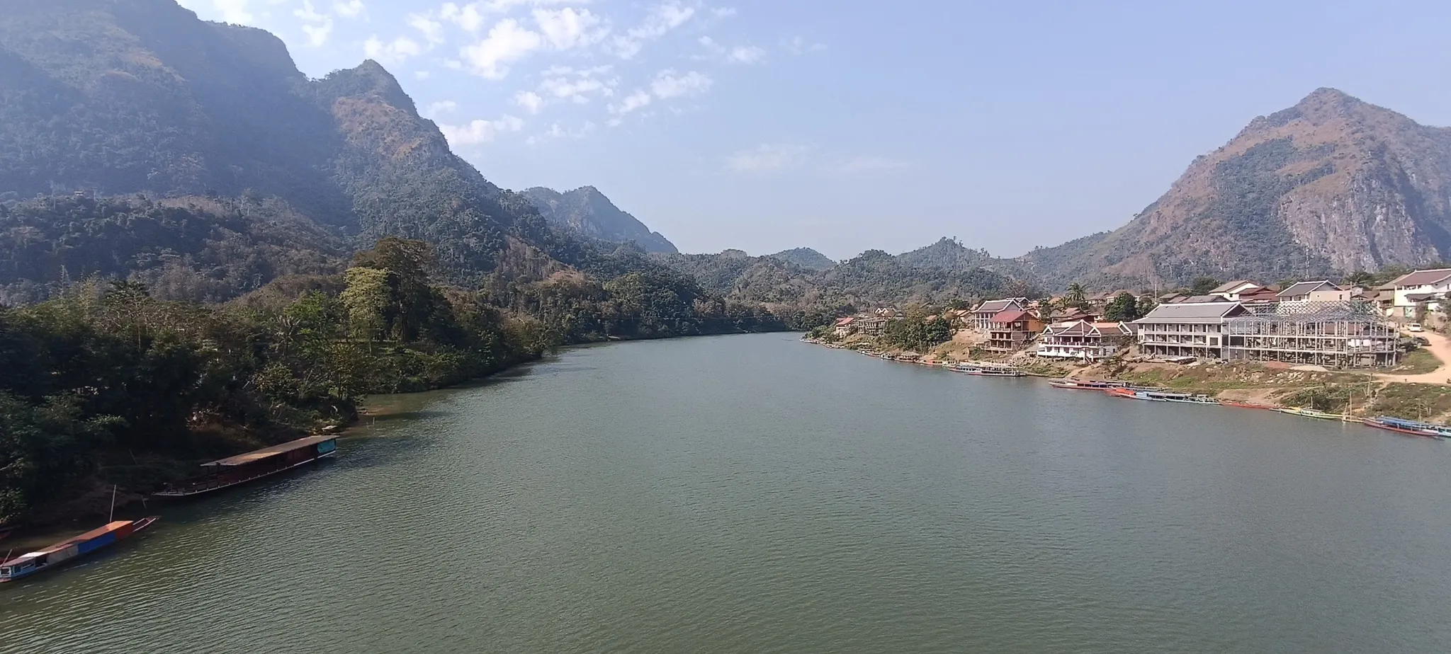 Nam Ou river at Nong Khiaw with colourful longboats moored and riverside guesthouses beneath karst peaks