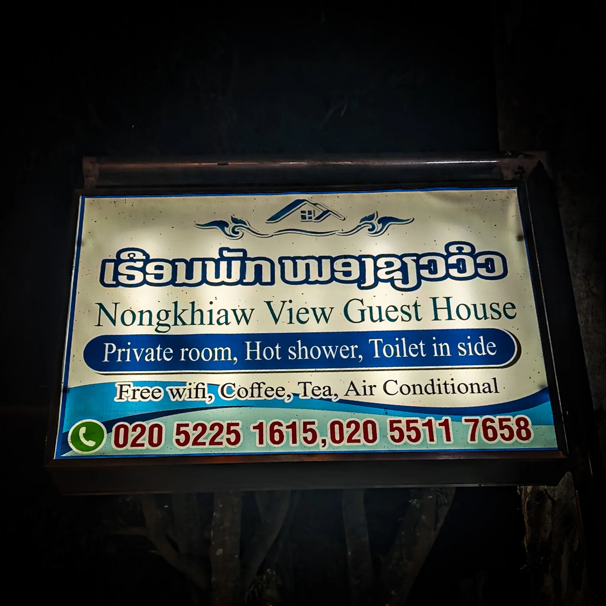 Illuminated sign for Nongkhiaw View Guest House showing amenities including private rooms and hot showers
