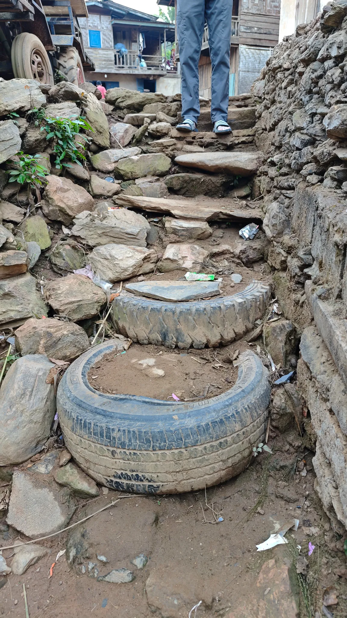 Improvised stone and recycled tyre steps on a steep village path between houses in Ban Haddean, Phongsaly Province