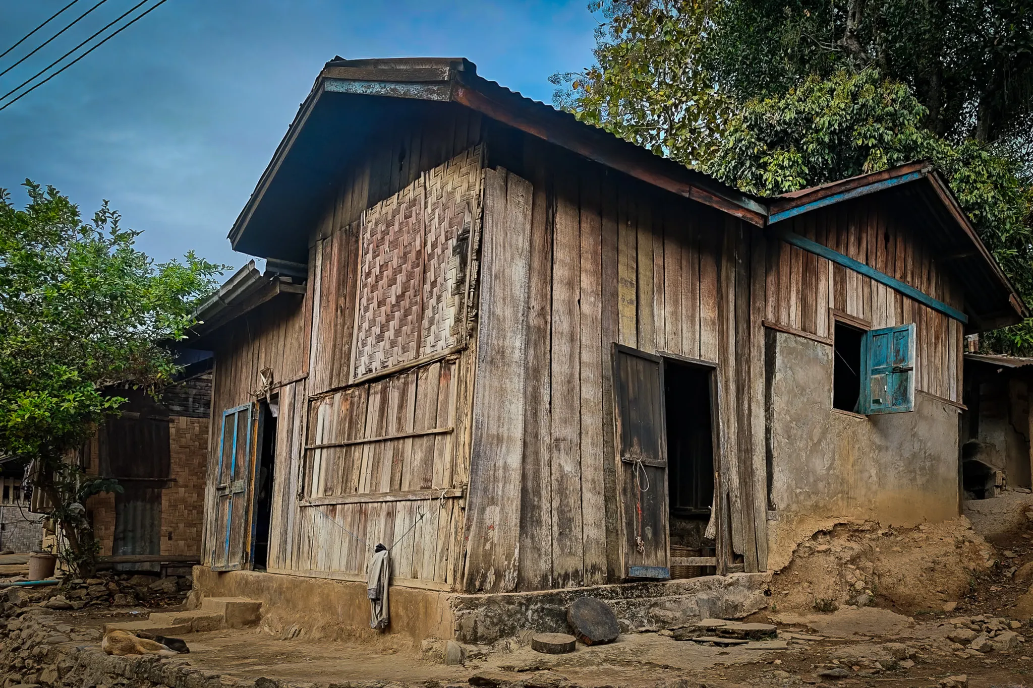 Traditional two-storey wooden house with weathered timber walls and a tin roof in Ban Haddean village near the Nam Ou