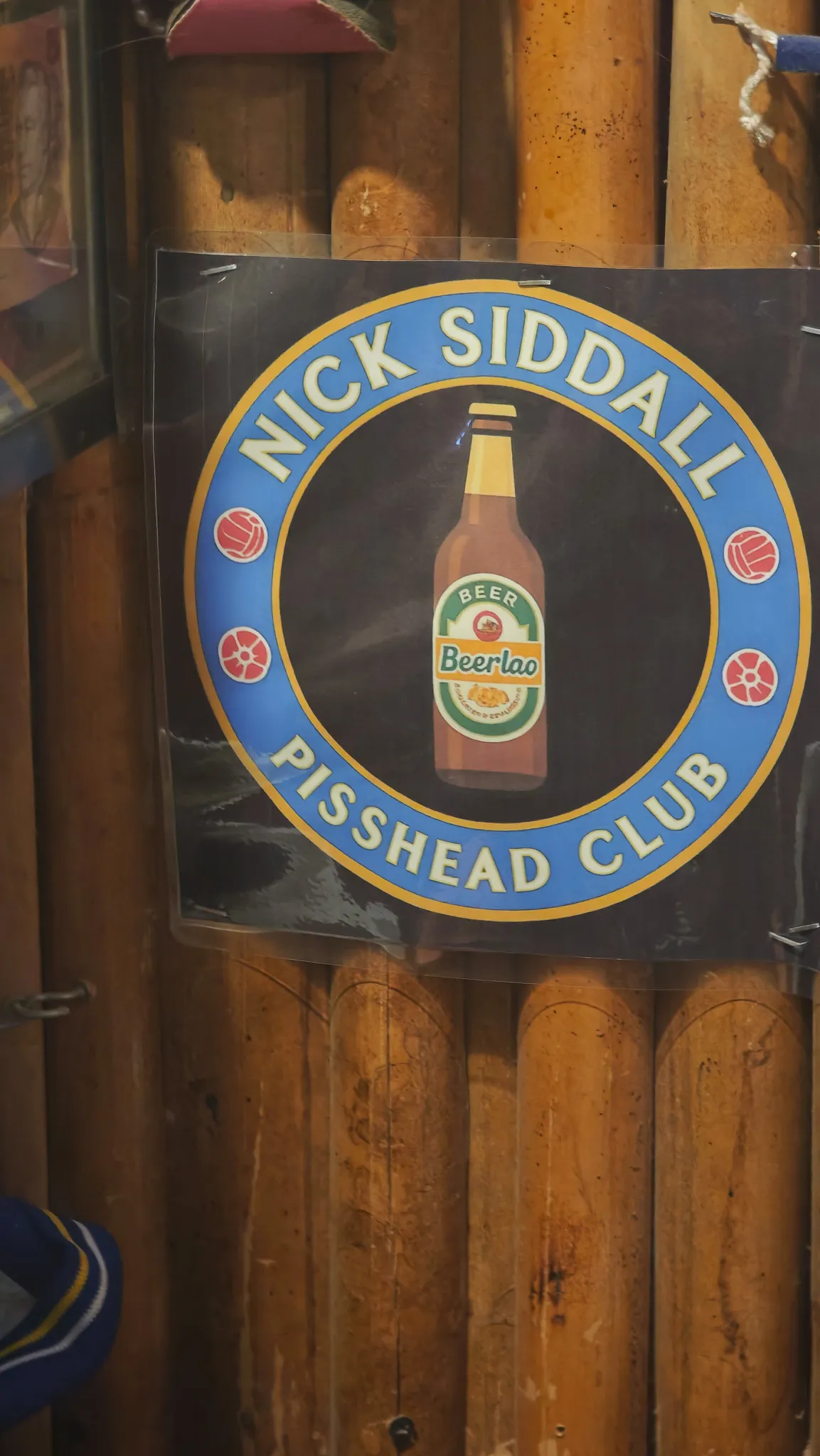 Nick Siddall Pisshead Club sign with a Beer Lao bottle illustration at a bar in Vang Vieng