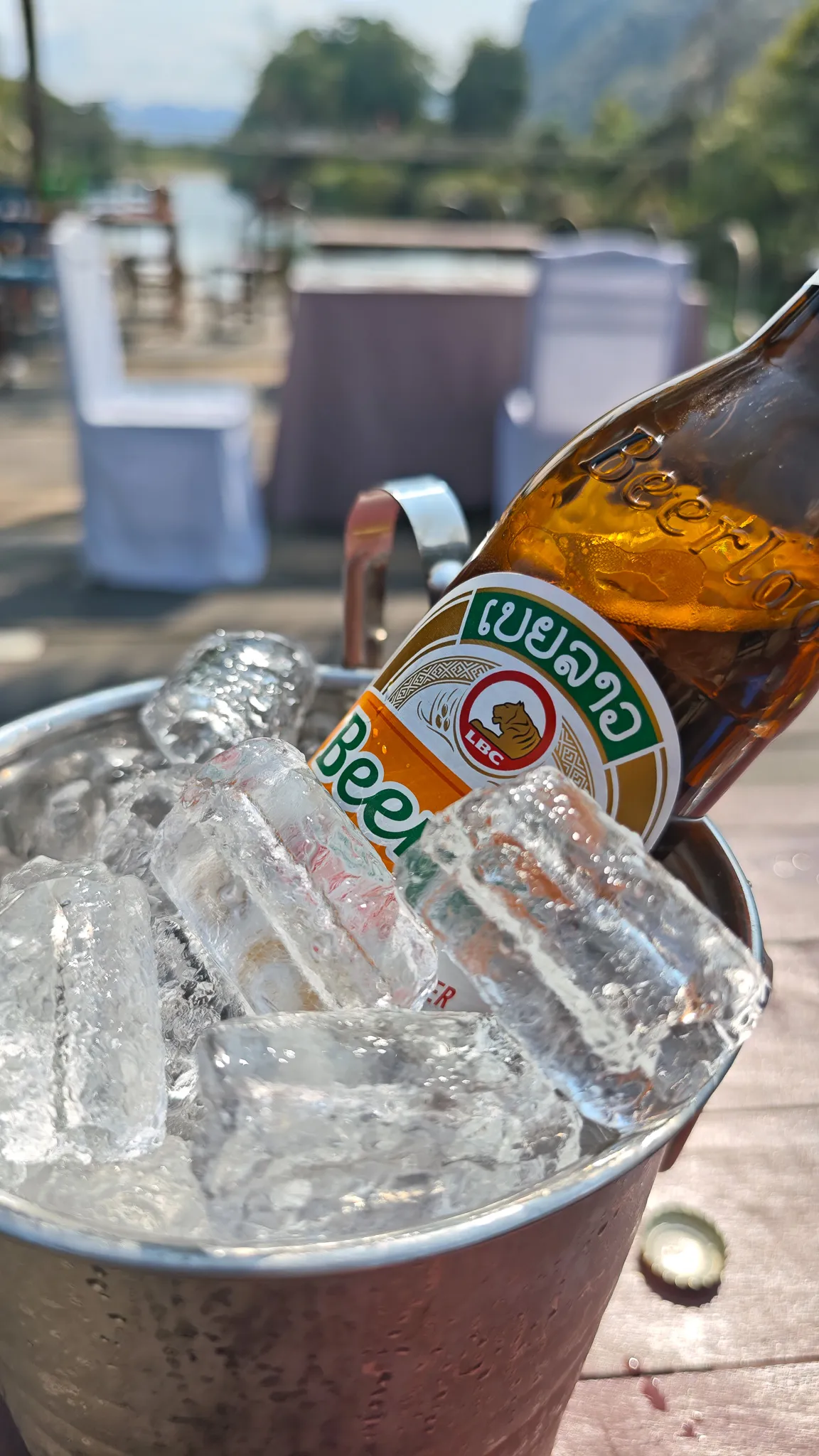 Portrait close-up of a Beer Lao bottle chilling in an ice bucket at a Vang Vieng riverside bar