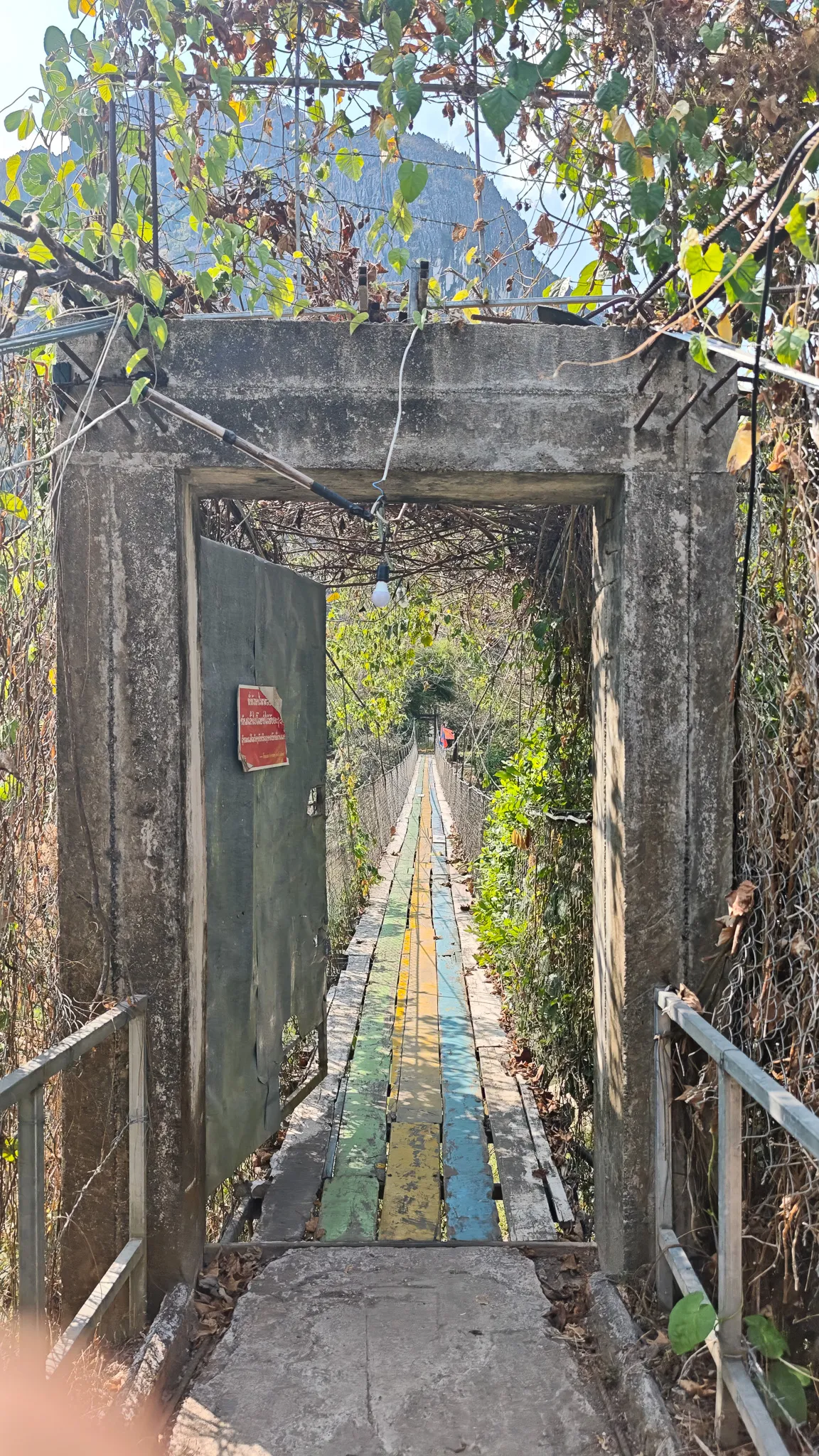 Entrance to a colourful narrow suspension bridge crossing the Nam Song River in Vang Vieng