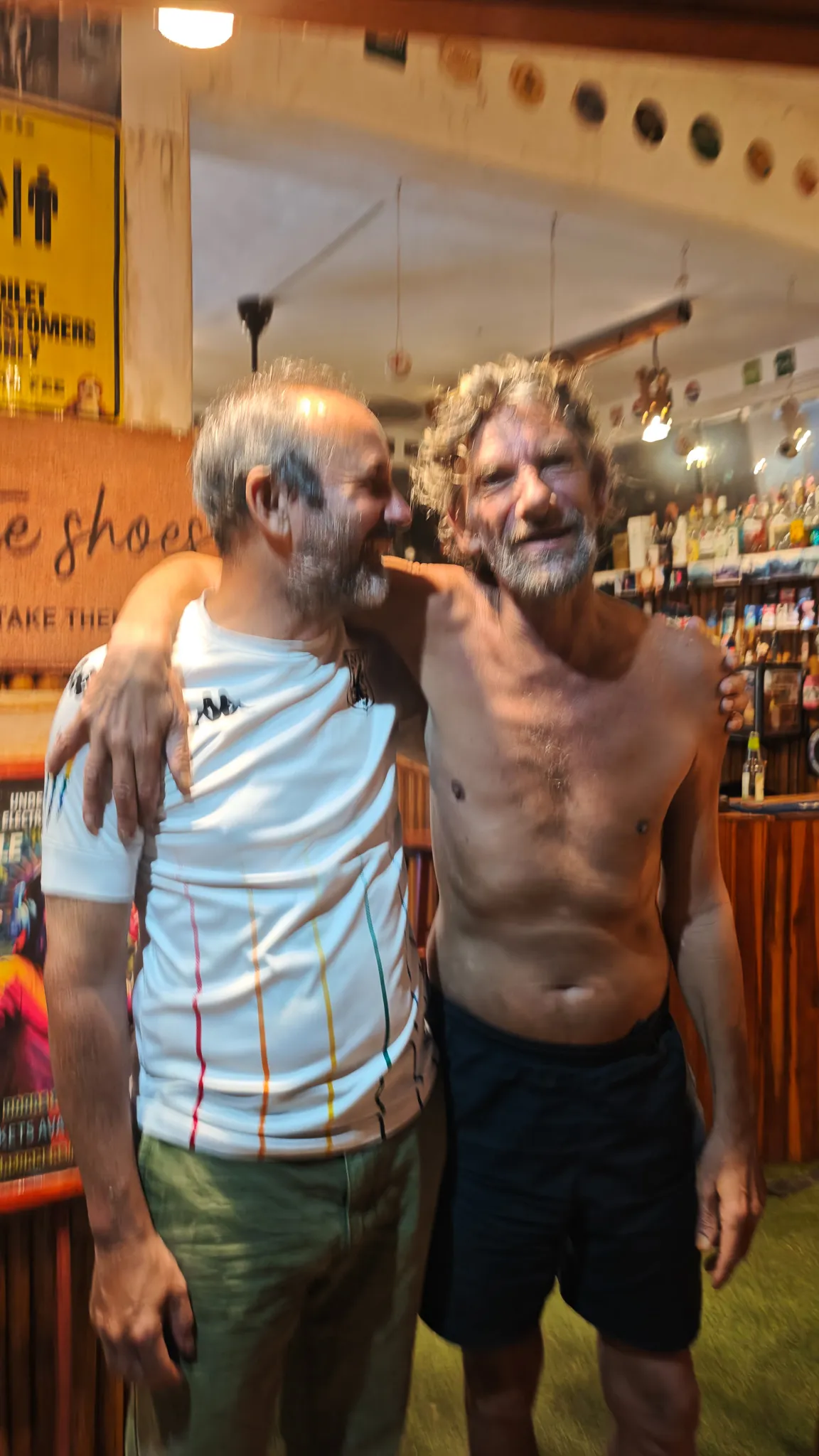 Laughing with the shirtless English bar owner at a dive bar packed with memorabilia in Vang Vieng