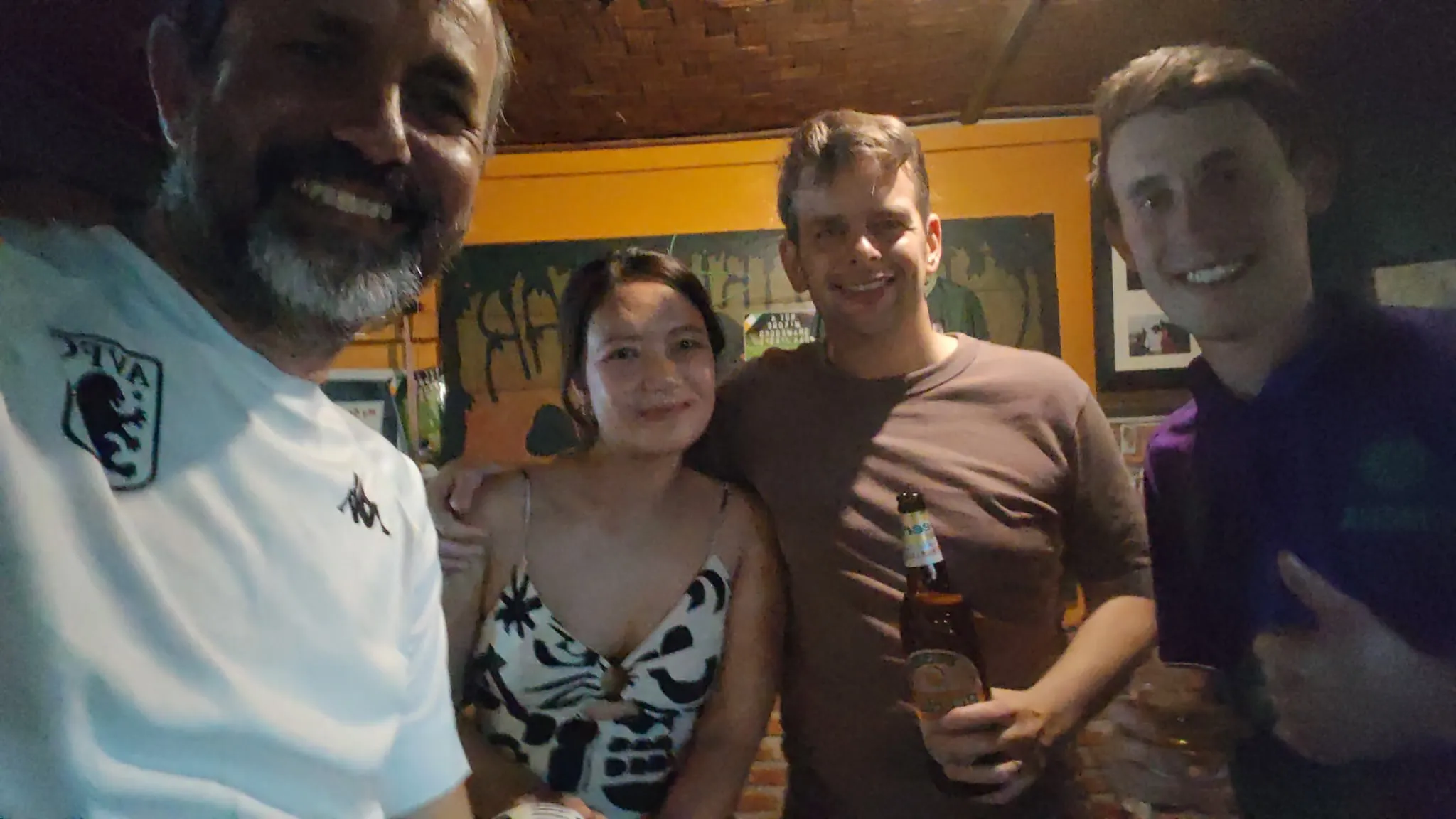Friends posing with Beer Lao bottles at a colourful bar in Vang Vieng nightlife