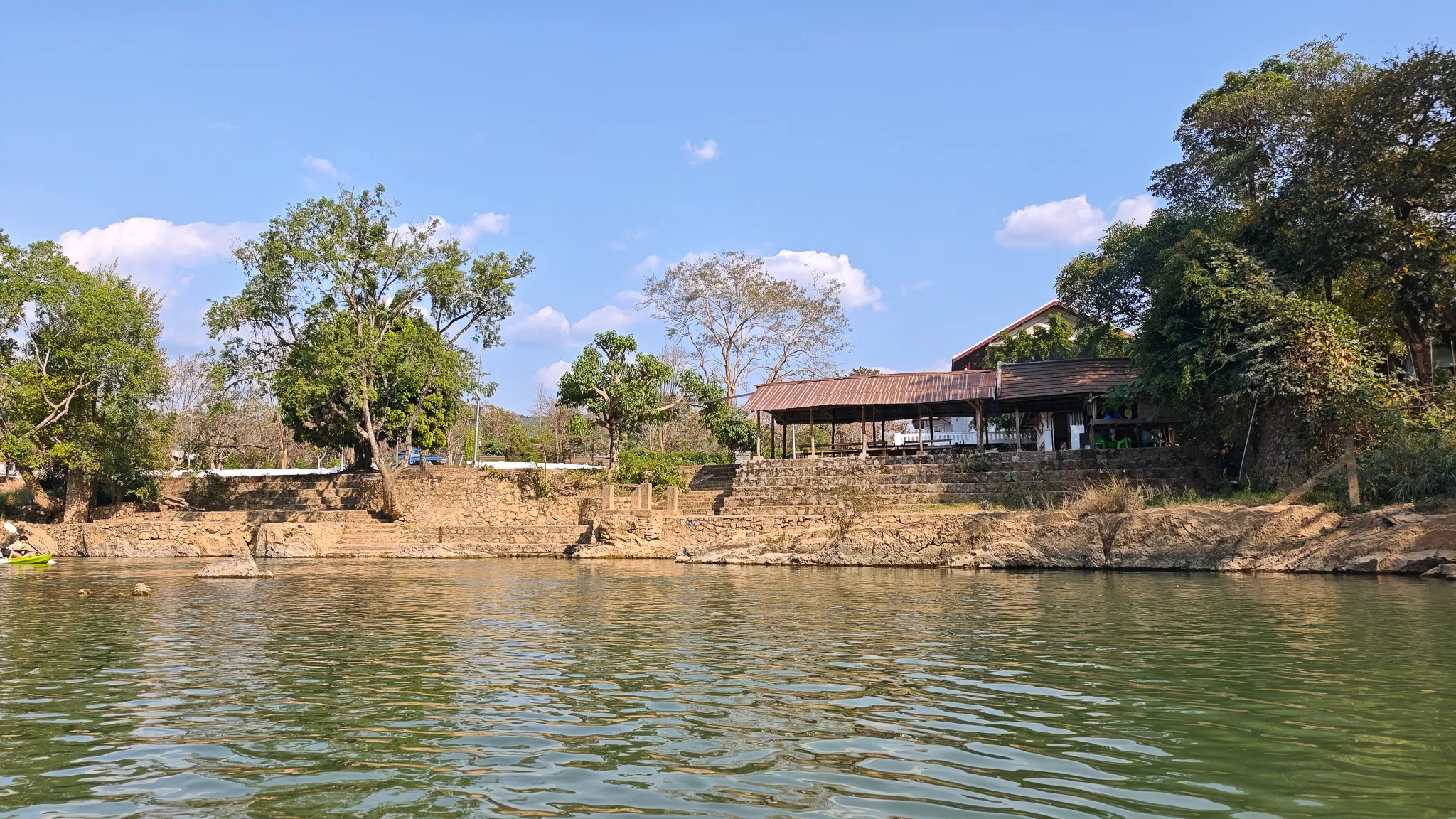 Riverside tubing bar stop along the Nam Song River with a covered structure and steps down to the water