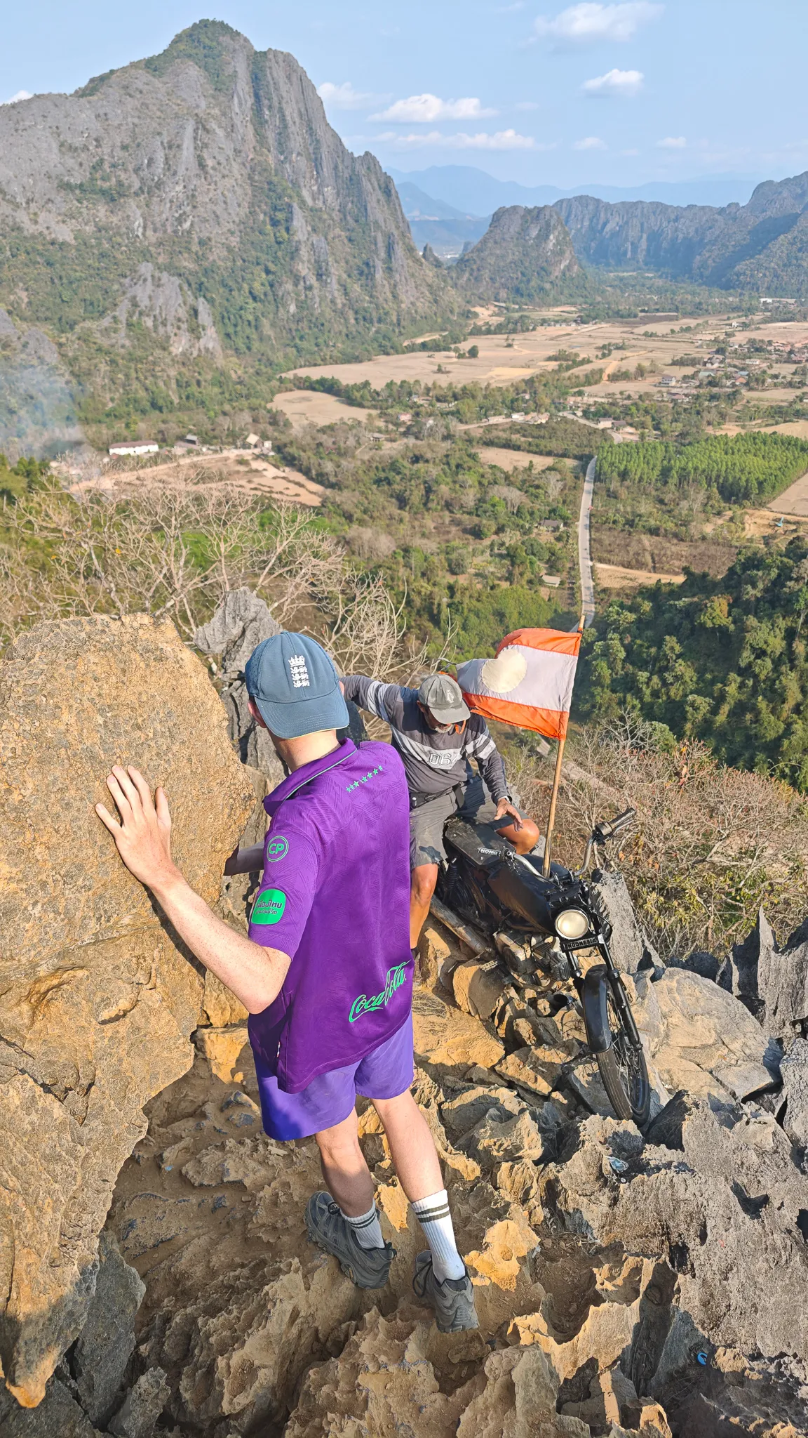 Approaching the Laos flag at the rocky summit of Nam Xay viewpoint with valley views in Vang Vieng
