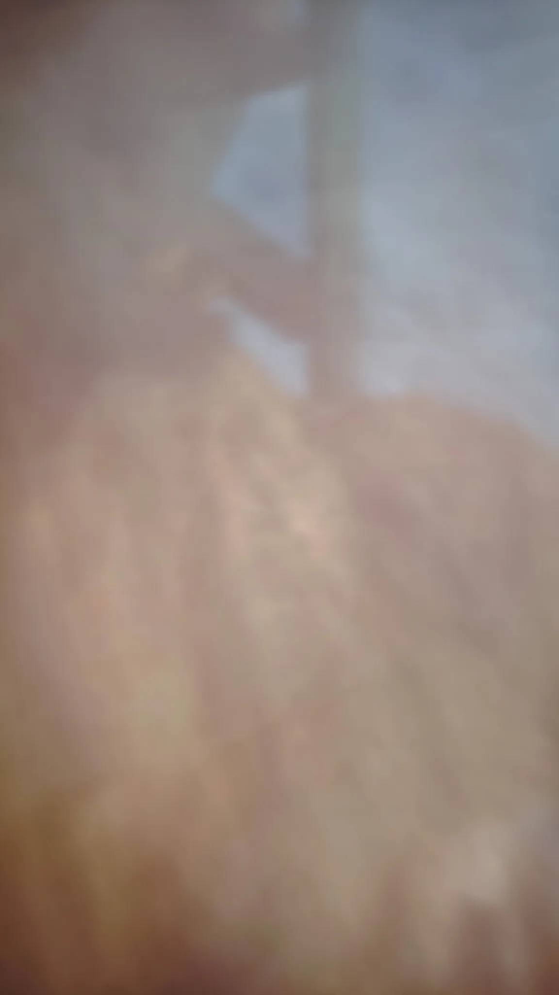 Looking up through dark cave rocks toward blue sky and a railing at Nam Xay viewpoint near Vang Vieng