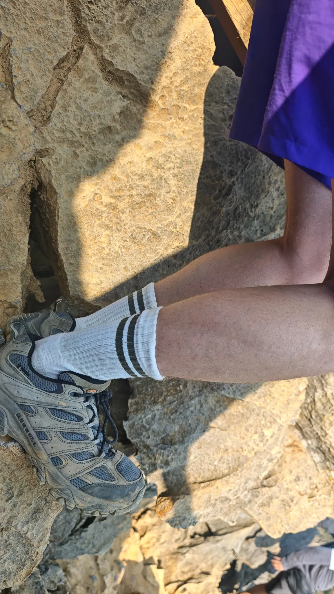 Climber scrambling over jagged rocks toward the Laos flag and motorcycle at the Nam Xay viewpoint summit
